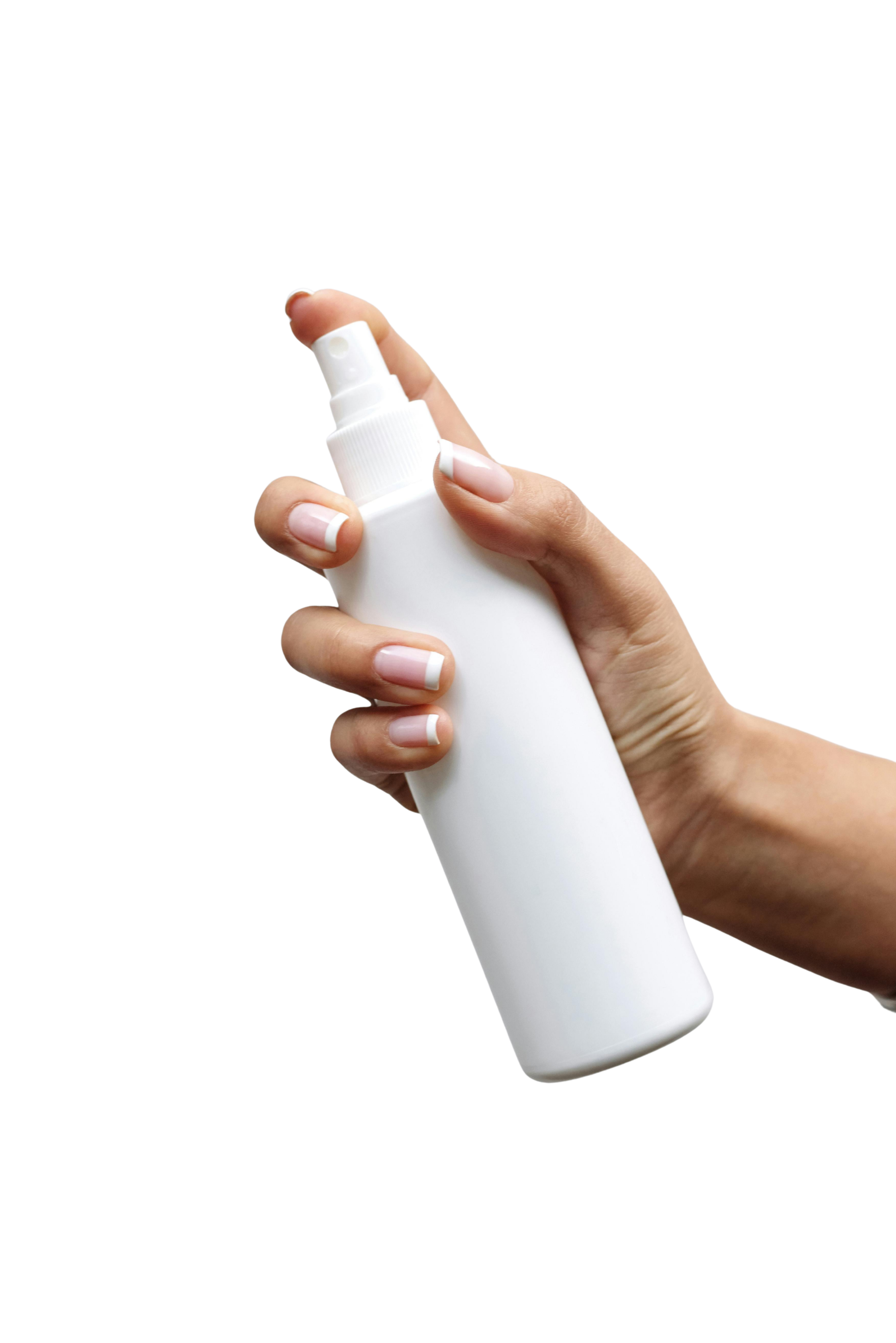 Hand holding a white spray bottle.