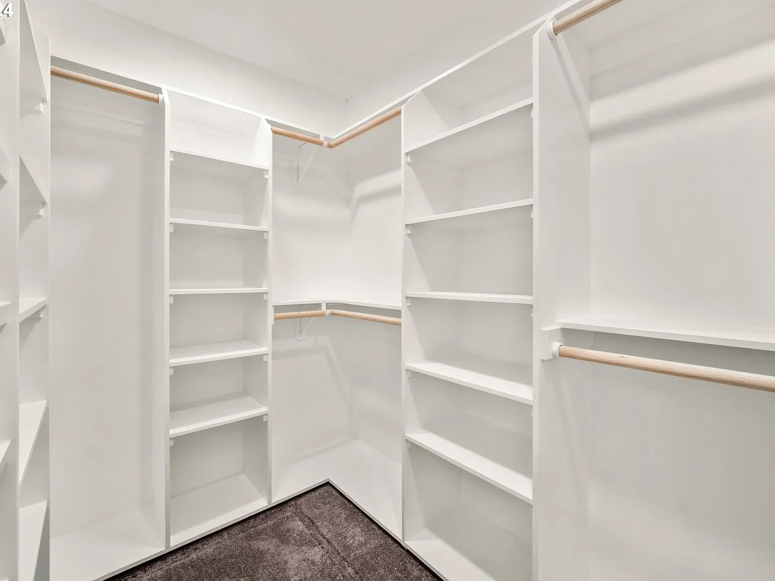 Empty white walk-in closet with built-in shelves and hanging rods