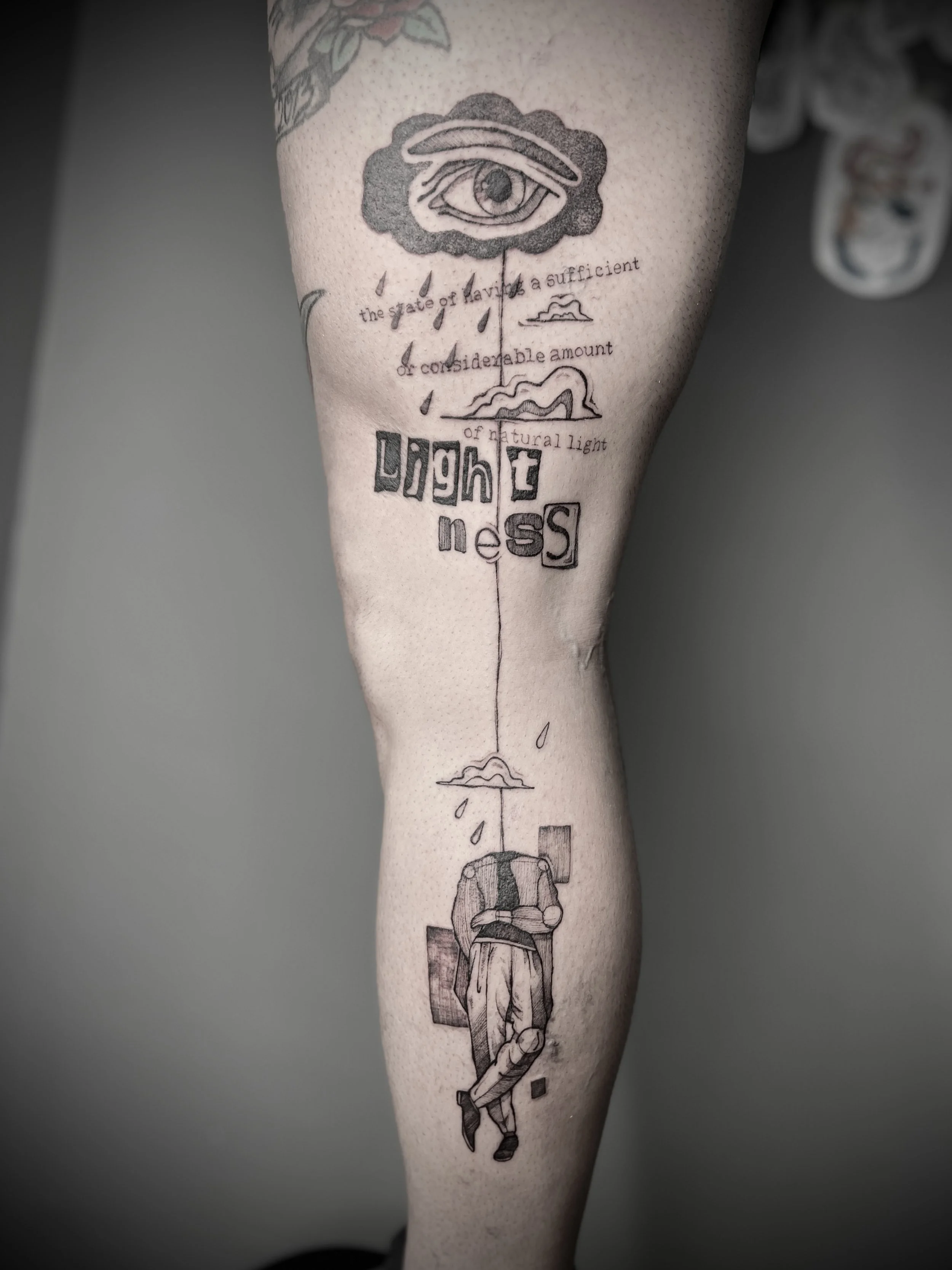 Tattoo sul, braccio di una persona che raffigura un occhio tra le nuvole, pioggia, e un uomo con uno zaino. Tra le nuvole ci sono anche delle gocce di pioggia e del testo in inglese e italiano.