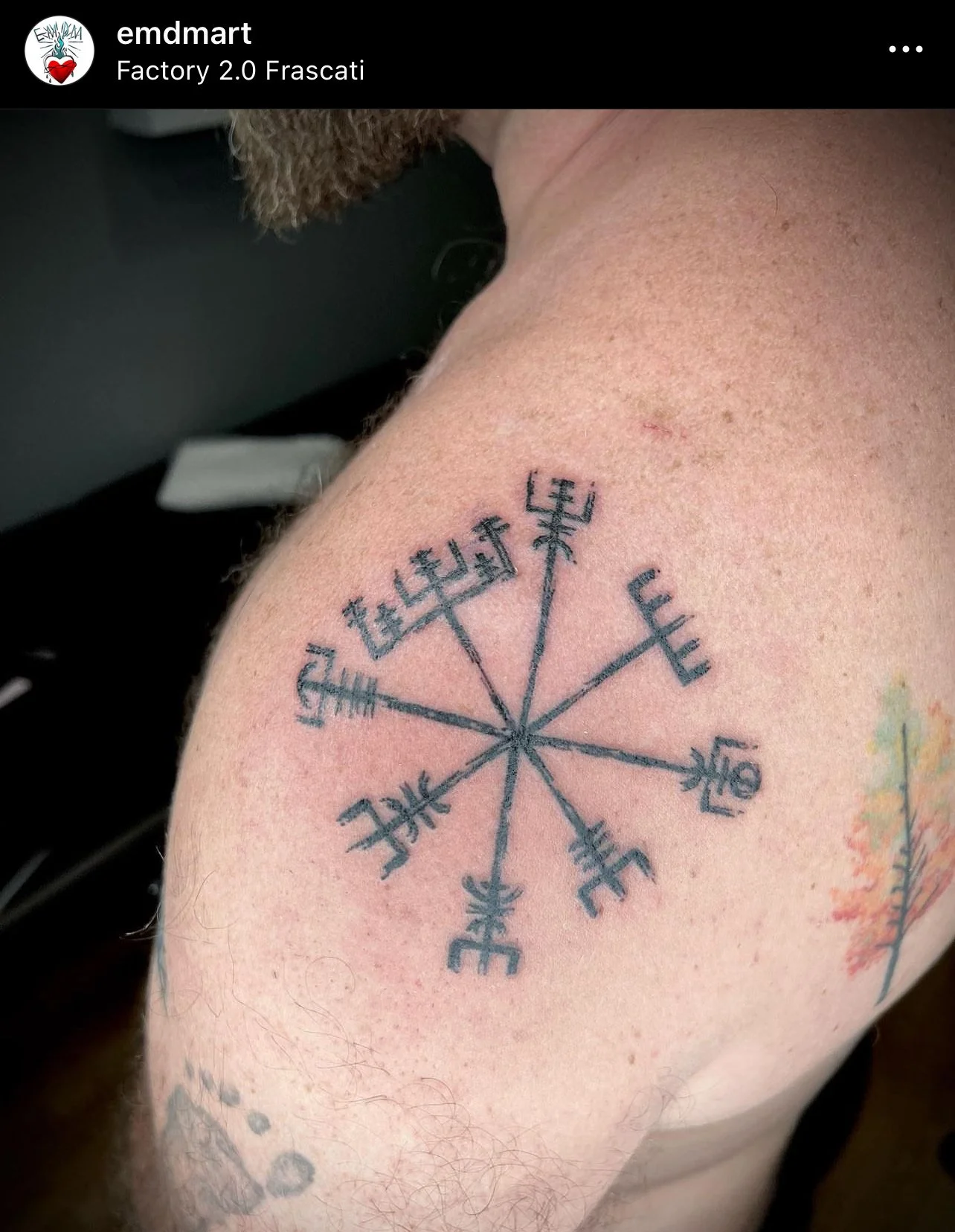 Tatuaggio di un simbolo runico sulla spalla di un uomo, con pelle leggermente arrossata.