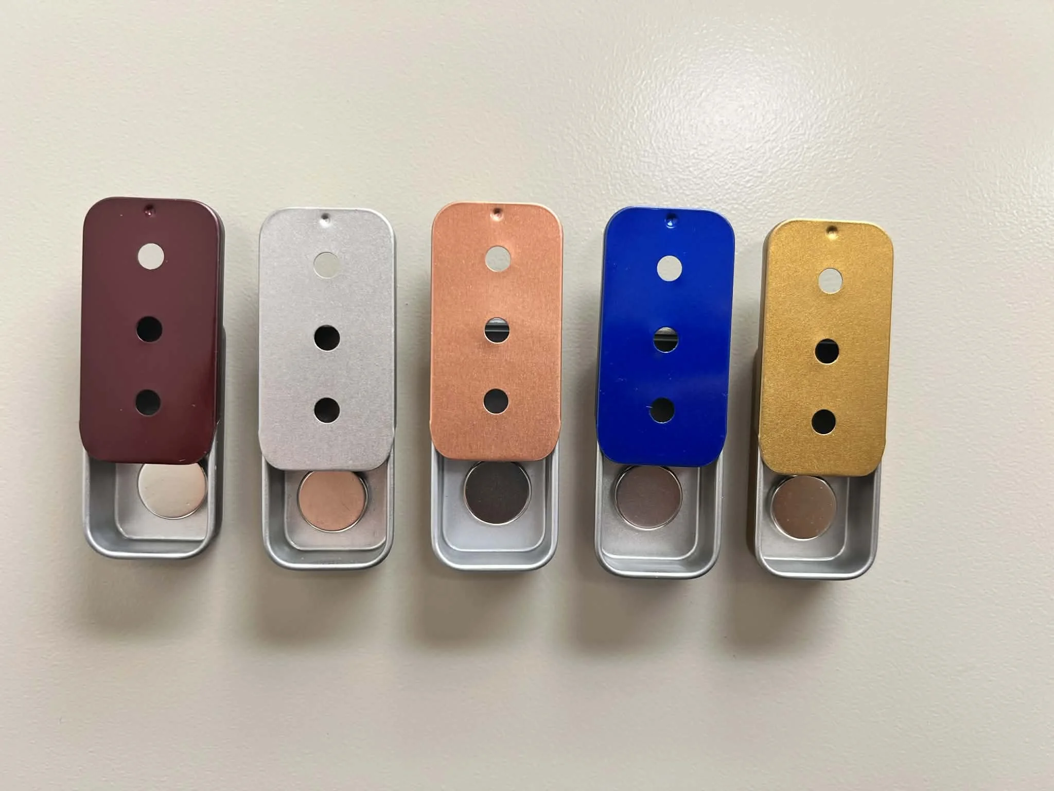 Three-hole magnetic slider tins in multiple colors for scent work training