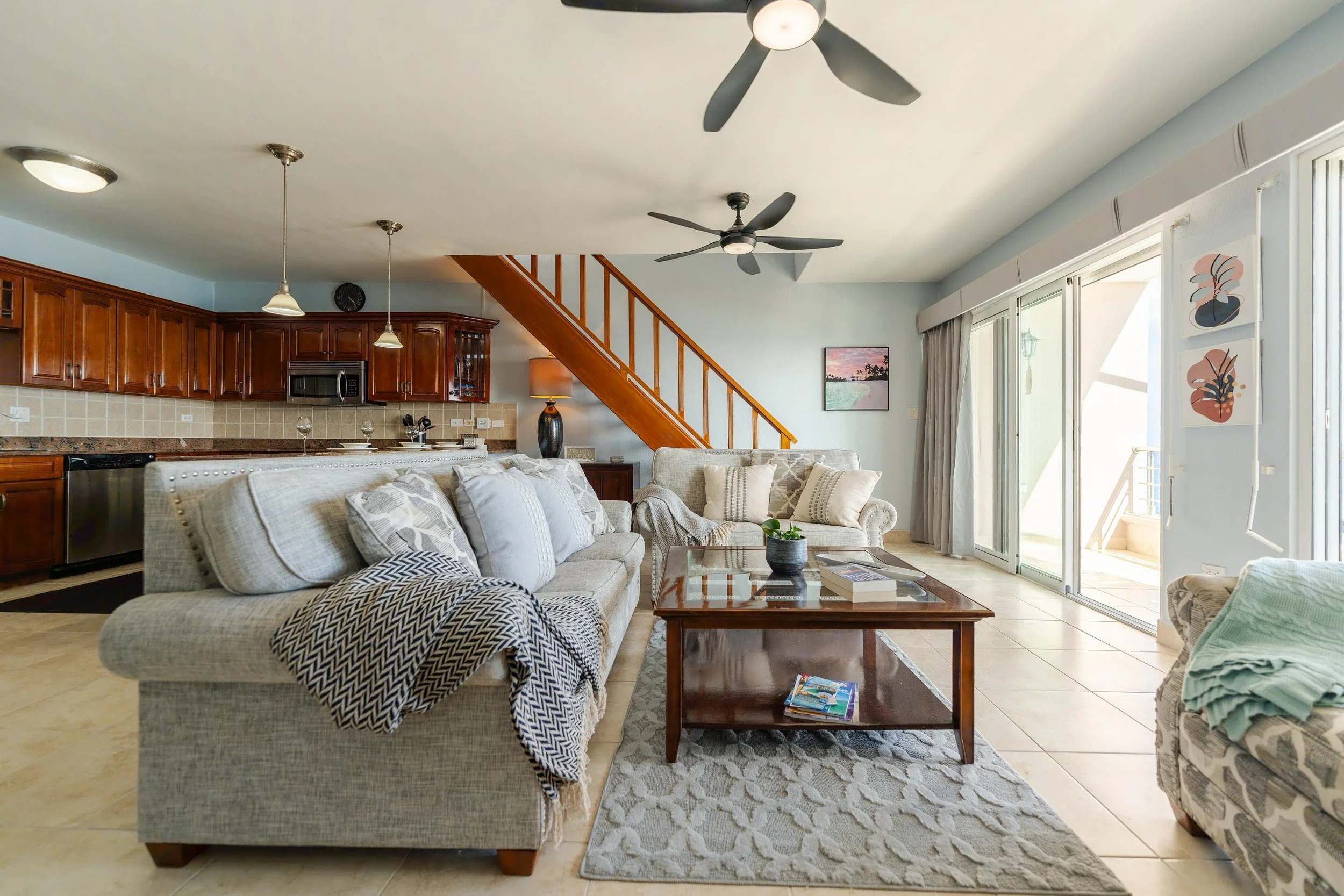 Living room with beige sofas, a wooden coffee table, and sliding glass doors leading to an outside balcony.