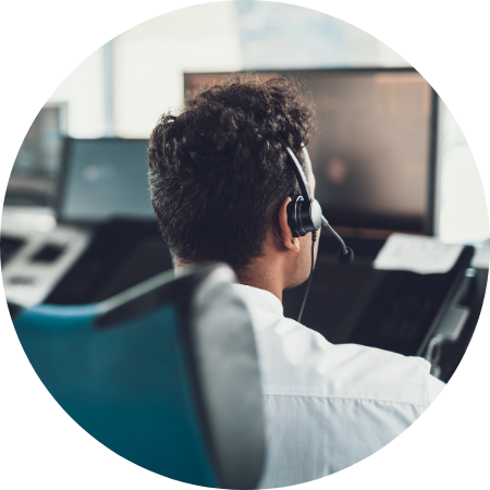 A group of people wearing headsets working at computers in a modern call center office with partitioned desks.