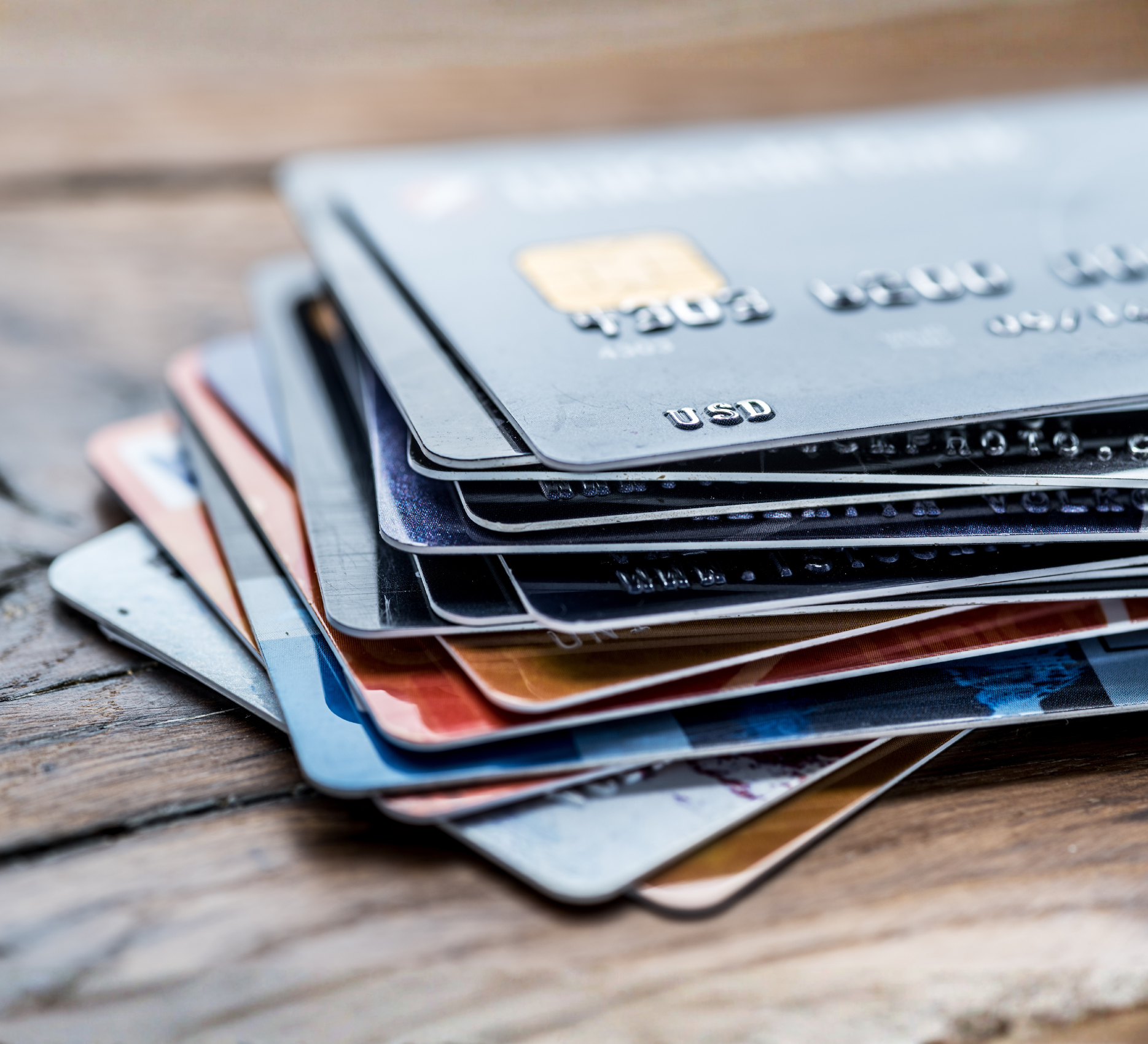 Stack of various credit cards on a wooden surface.