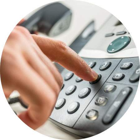 A person's finger pressing a button on a office phone.