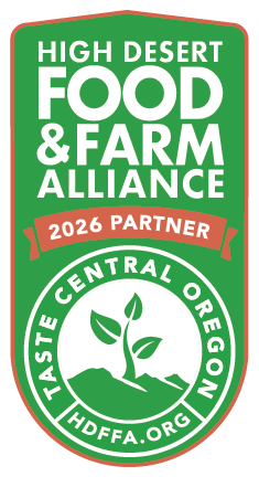 High Desert Food & Farm Alliance logo with a green background, white text, a red ribbon indicating partnership in 2026, and a circular emblem with a plant sprouting from the soil, representing Central Oregon.