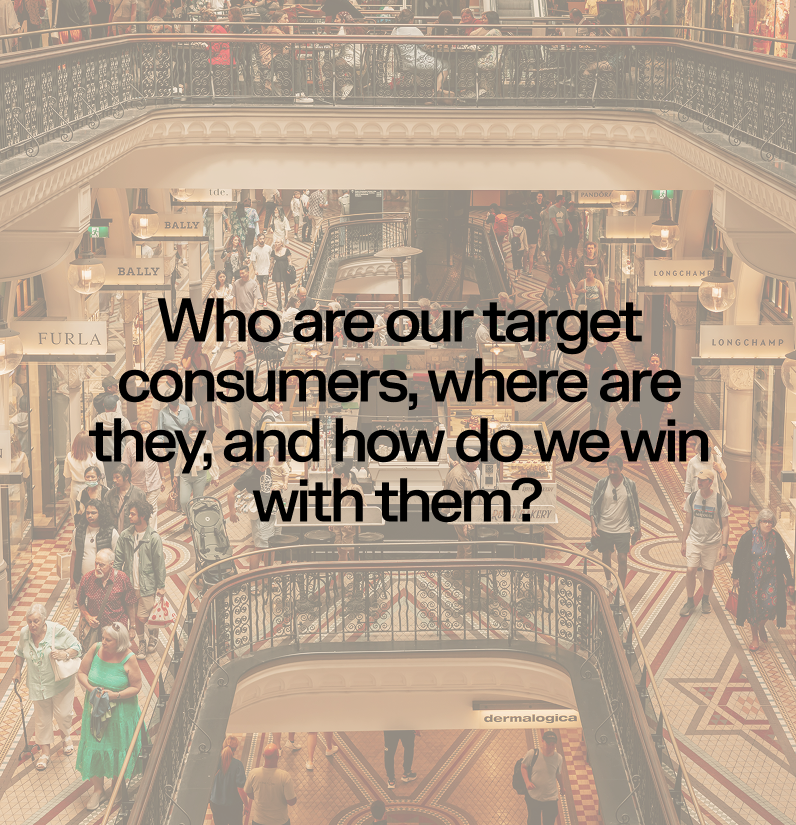Interior of a busy shopping mall with multiple levels, various stores, and many shoppers walking.