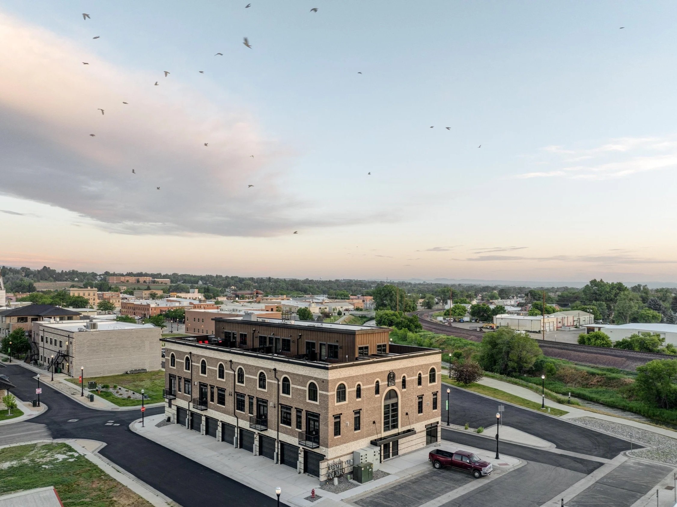 Aerial view of Ice Haus Condos in Sheridan, WY, showing a modern multi-story brick building, nearby streets, parking, and the surrounding neighborhood.