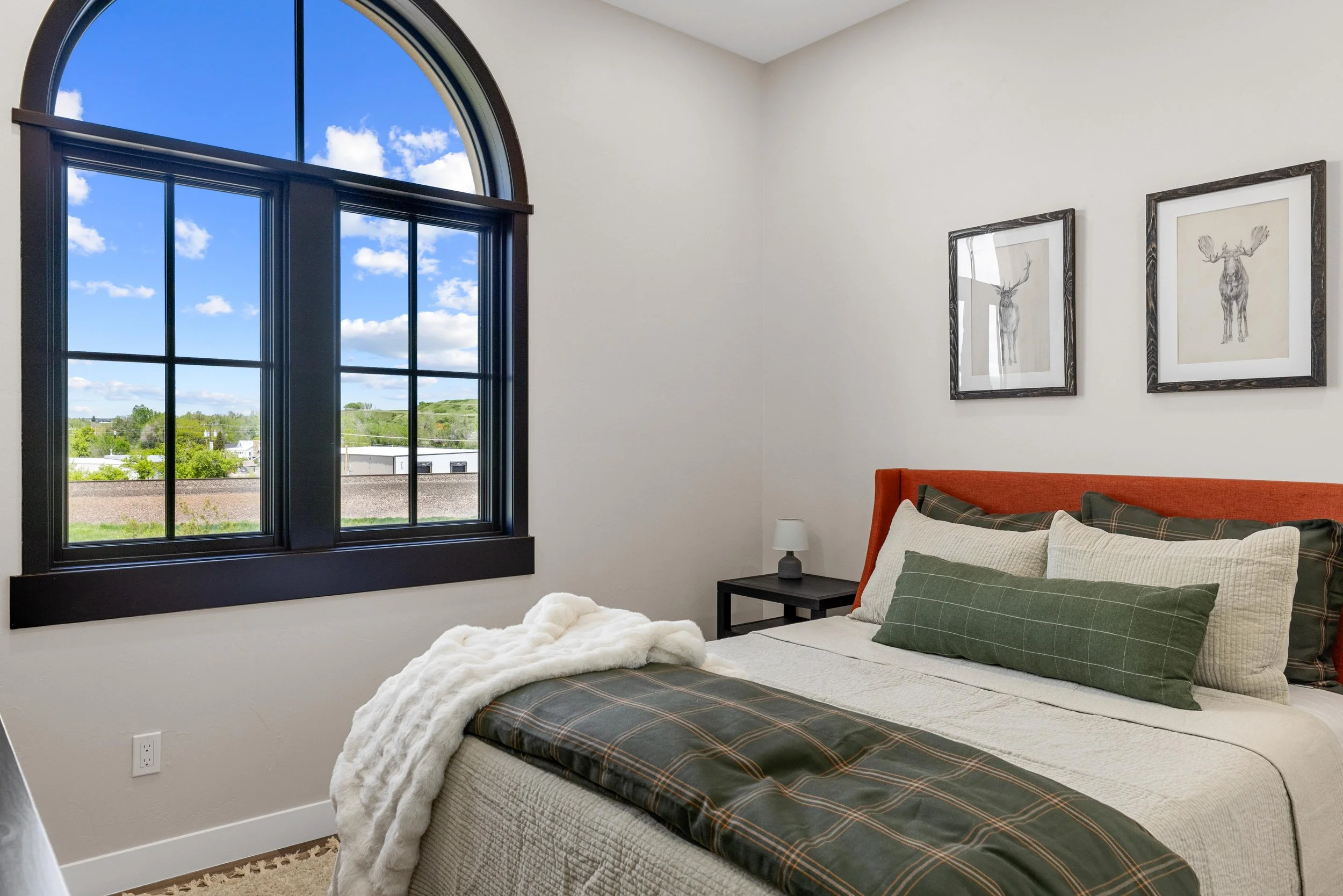 Cozy bedroom inside an Ice Haus Condo in Sheridan, WY, that is for sale with a large window, natural light, modern finishes, and comfortable mountain-style design.