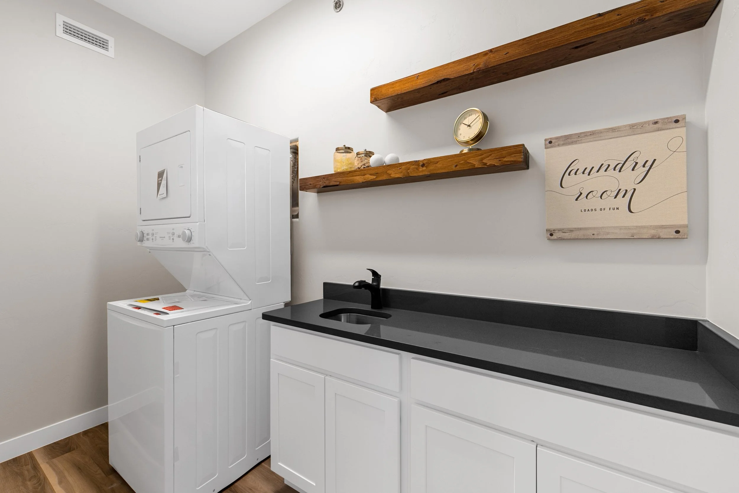 Dedicated laundry room inside an Ice Haus Condo for sale in Sheridan, WY with stacked washer and dryer, white cabinetry, sink, and modern finishes.