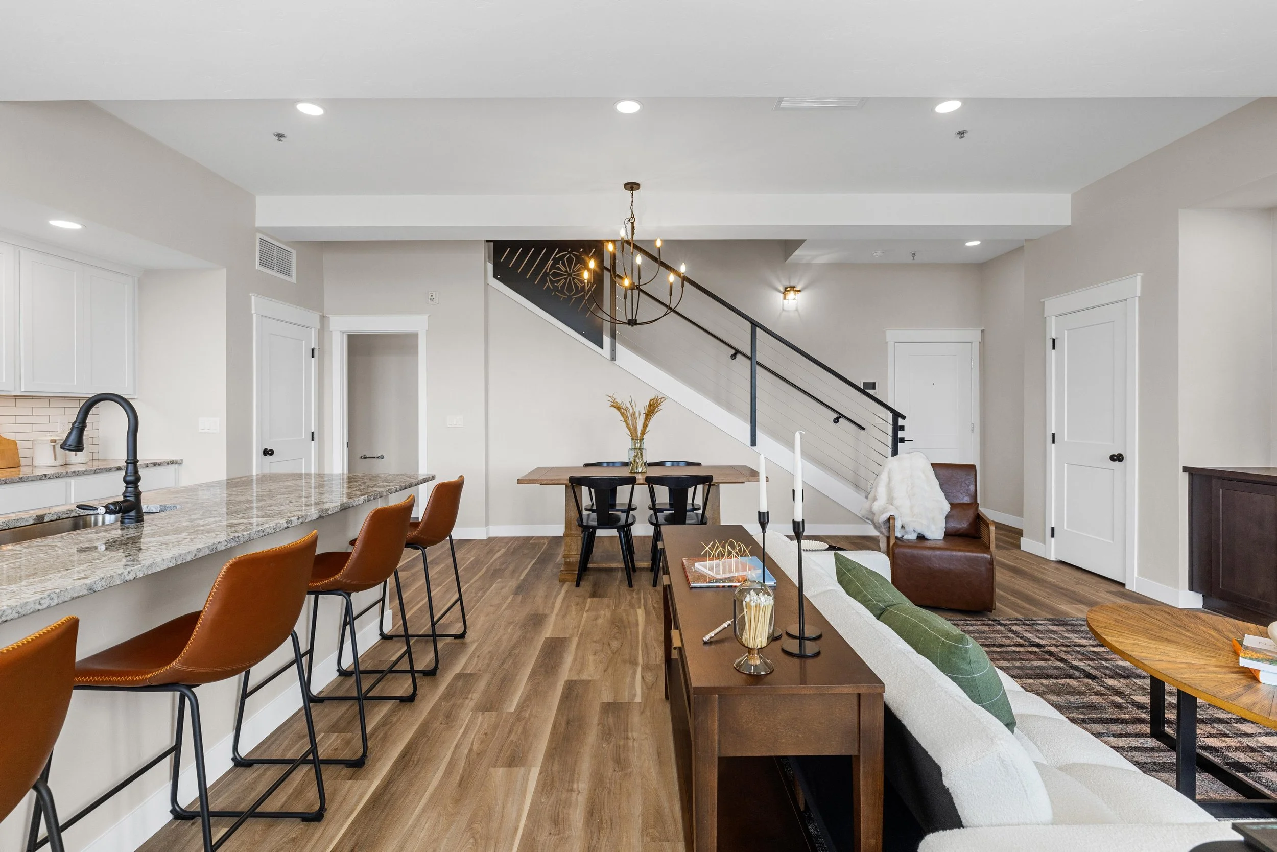 Open-concept living and dining area inside an Ice Haus Condo for sale in Sheridan, WY with hardwood floors, modern staircase, and clean contemporary style.