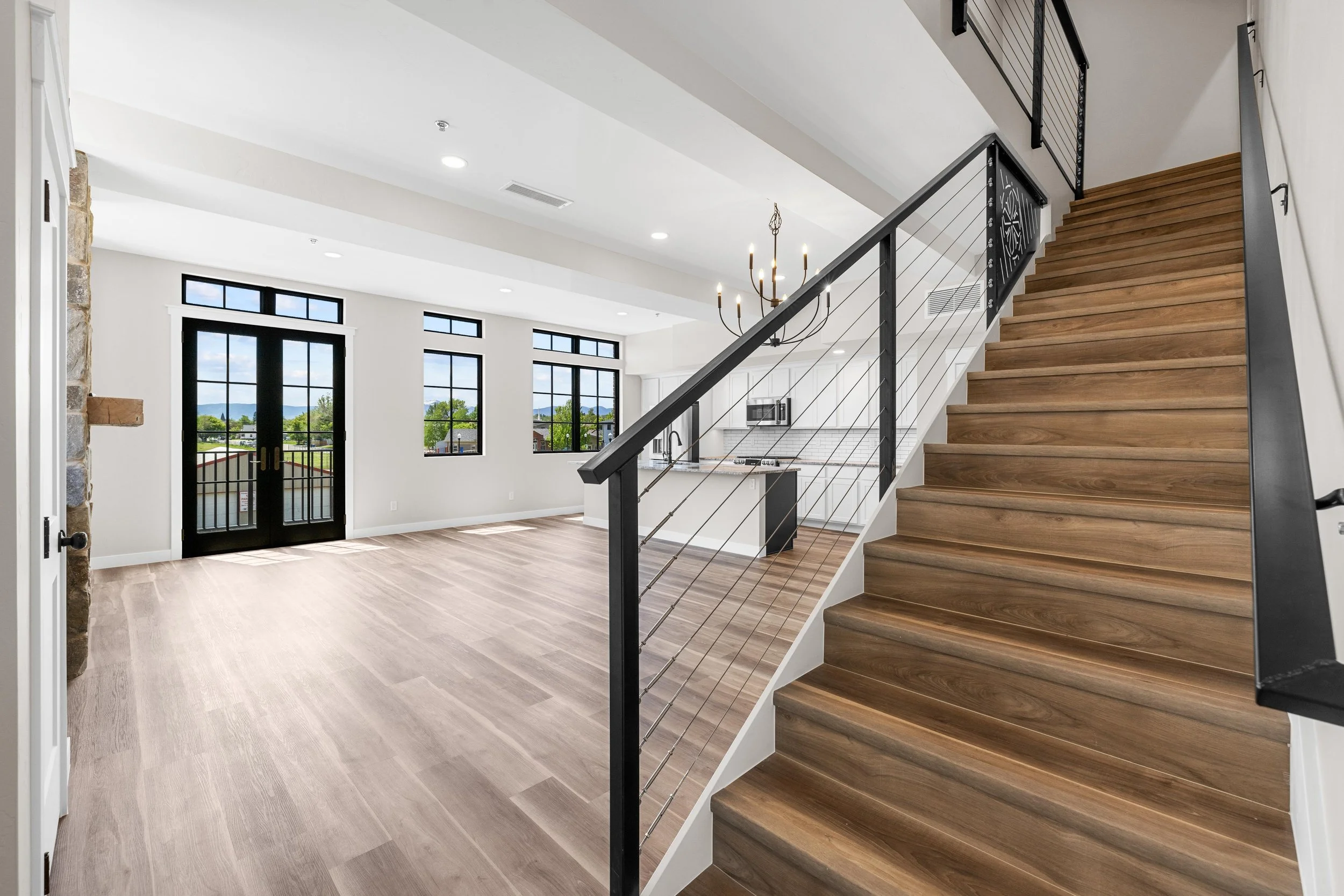Open-concept living space inside an Ice Haus Condo in Sheridan, Wyoming with wood floors, modern staircase, large windows, and bright contemporary interior.