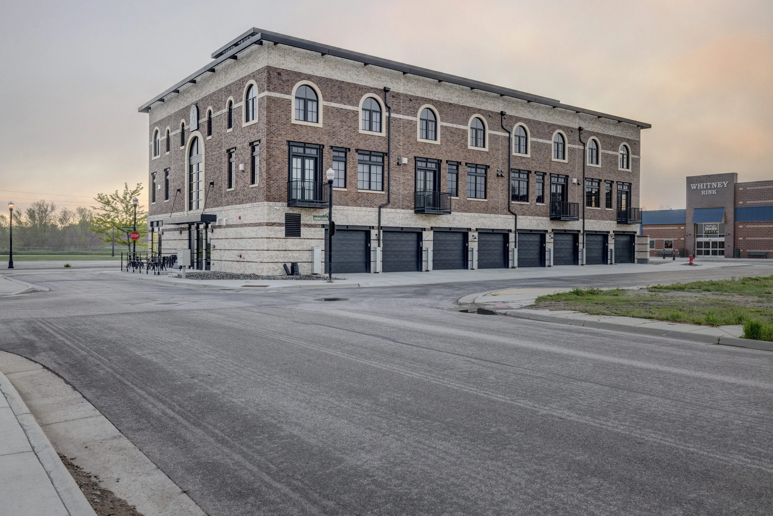 Exterior of Ice Haus Condos in Sheridan, Wyoming featuring modern brick architecture, arched windows, black garage doors, and walkable city streets.