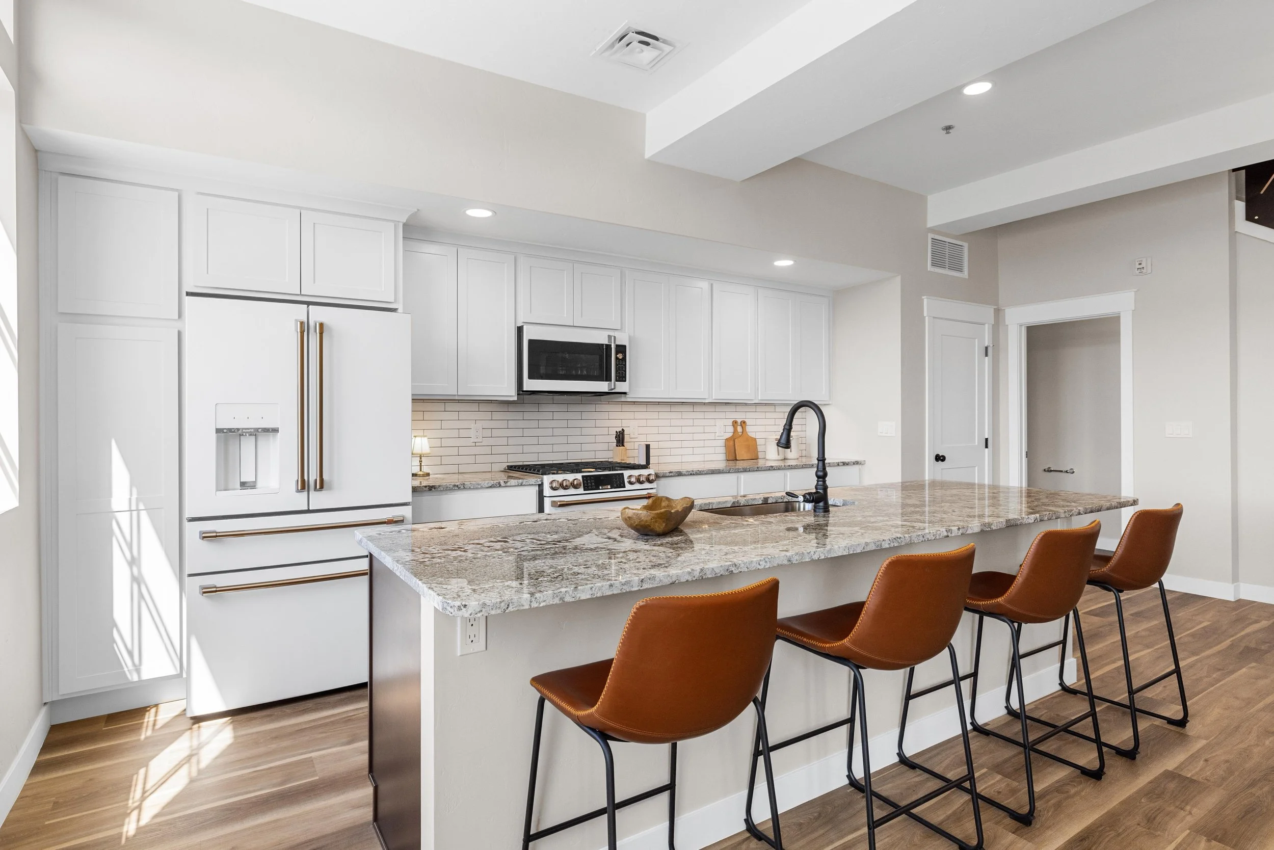 Open-concept living and dining room inside an Ice Haus Condo for sale in Sheridan, Wyoming featuring modern chandelier, hardwood flooring, and spacious layout.