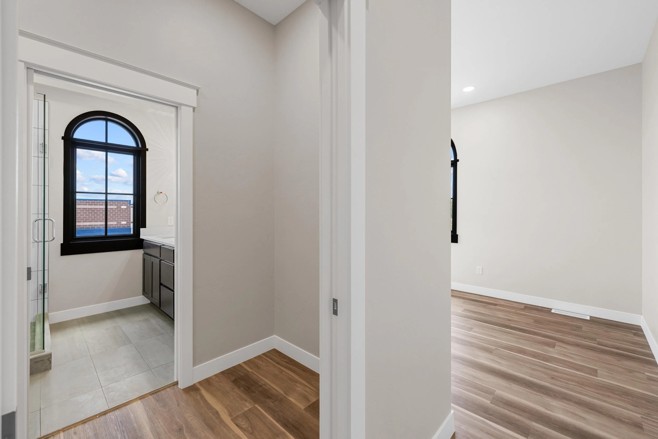 Empty rooms with beige walls, black window frames, and hardwood flooring in an Ice Haus Condo for sale in Sheridan, Wyoming.