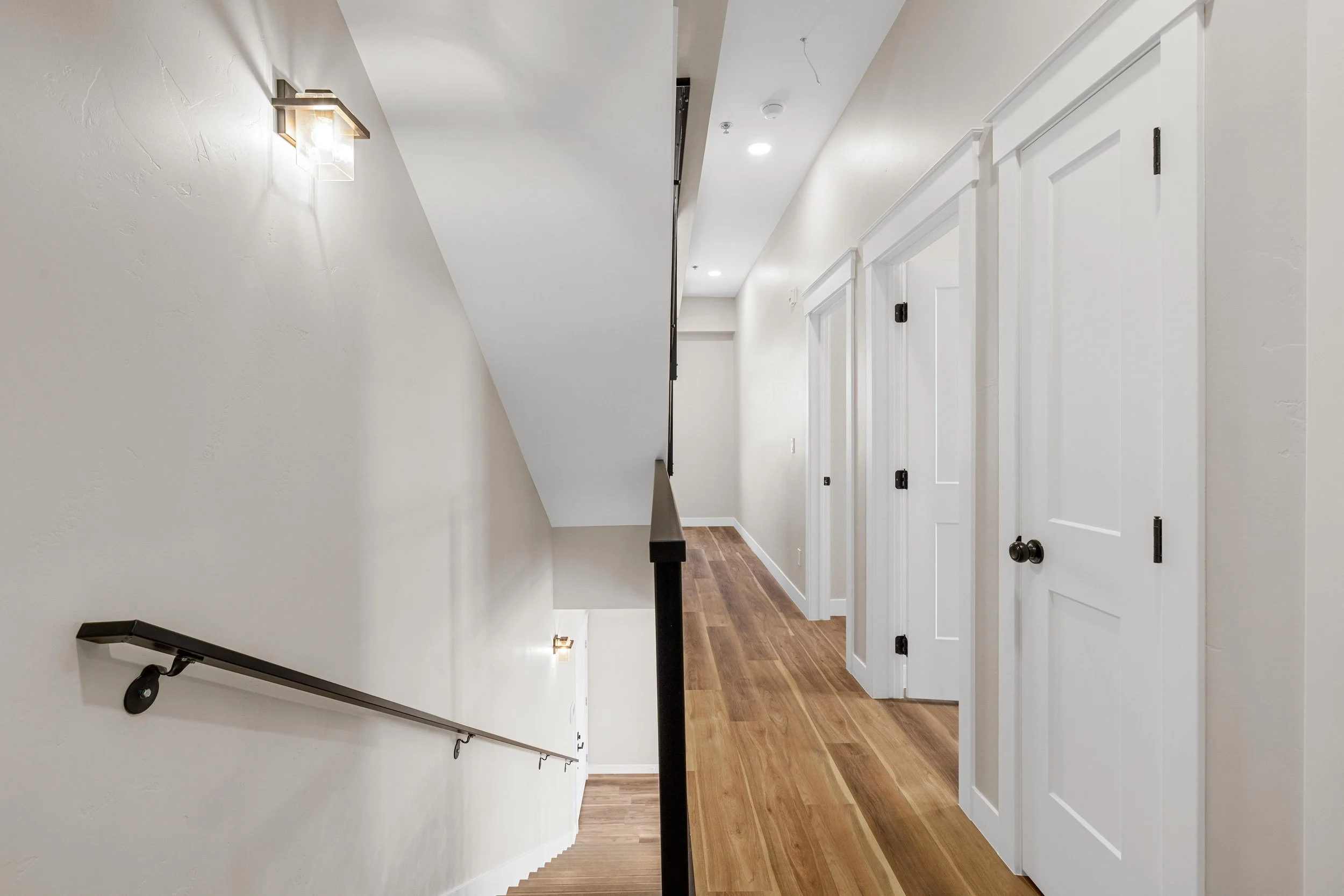 Interior view of a staircase and hallway in an Ice Haus Condo for sale in Sheridan, Wyoming, with white walls, wooden flooring, and white doors.