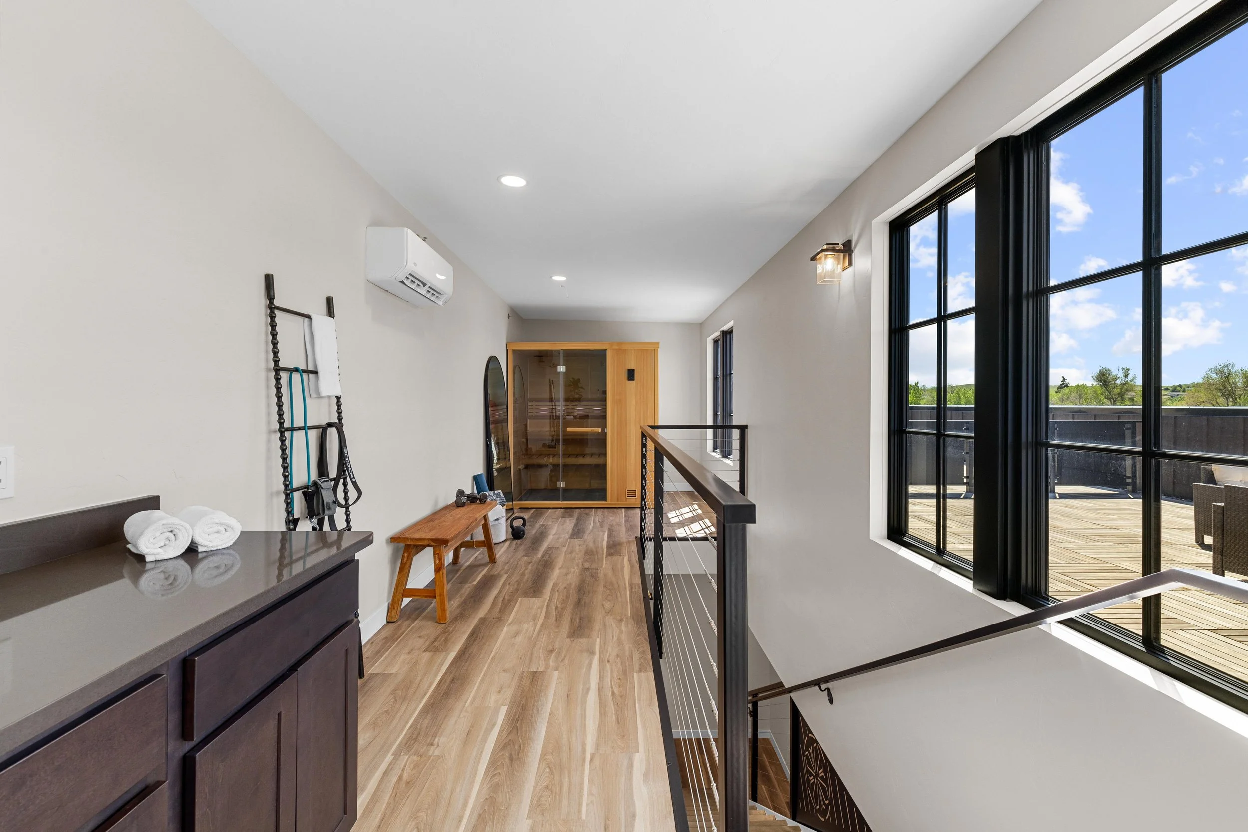 Interior view of a hallway in an Ice Haus Condo for sale in Sheridan, Wyoming, with large windows, wooden flooring, and a sauna at the end.