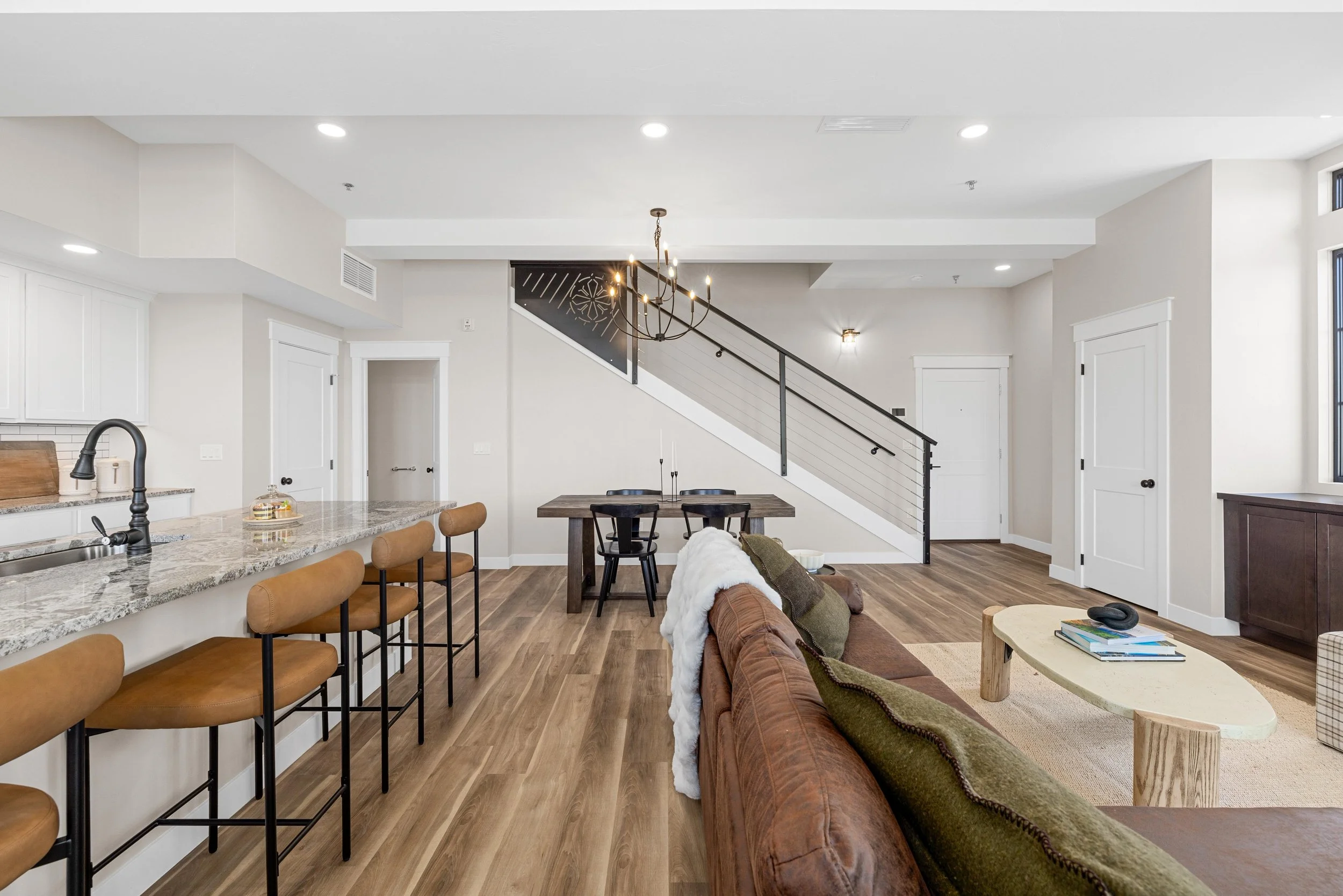 Open-concept living room with kitchen island, dining area, staircase, and seating.