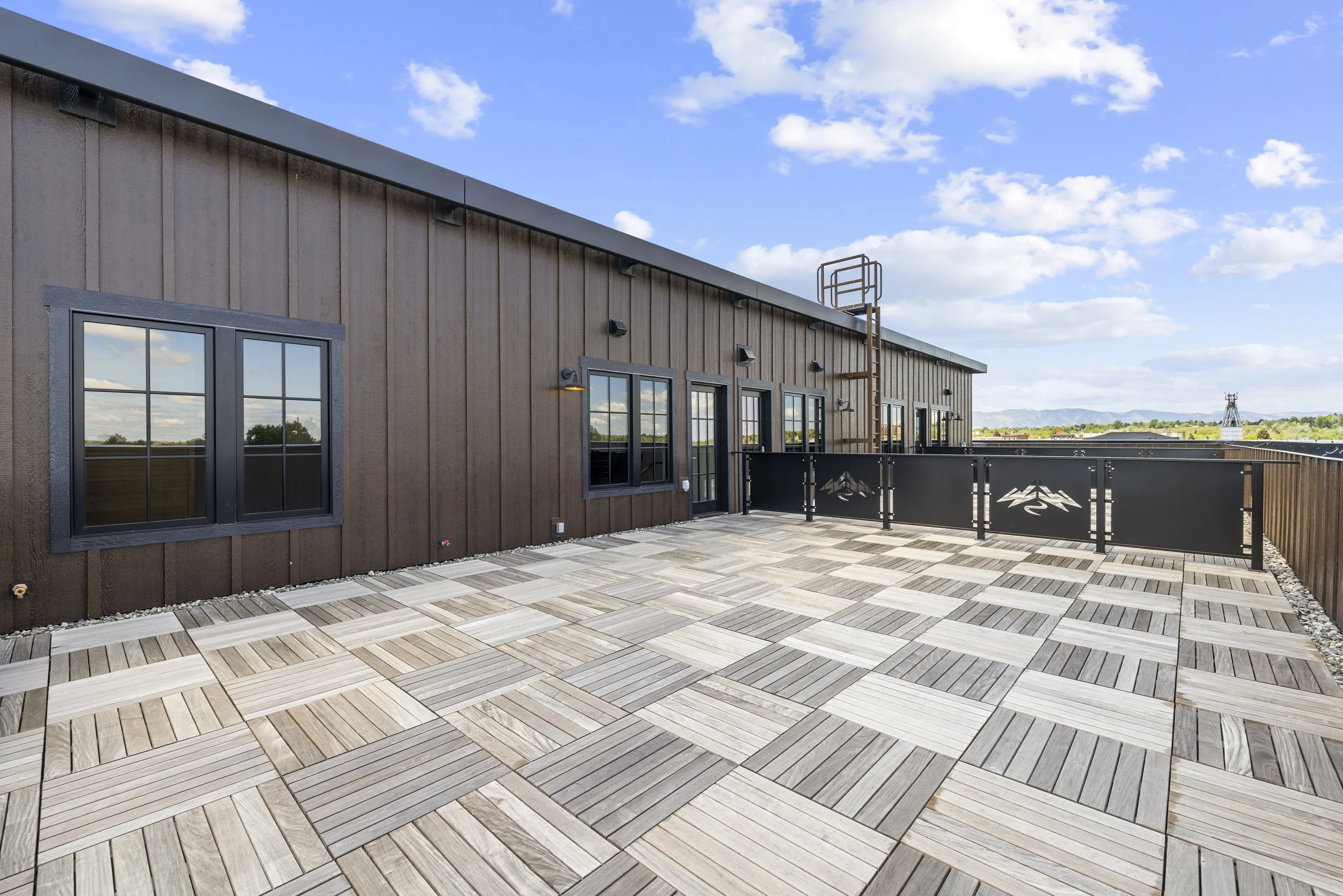 Rooftop deck at Ice Haus Condos for sale in Sheridan, Wyoming offering wood tile flooring, modern architecture, and open-air outdoor living space.