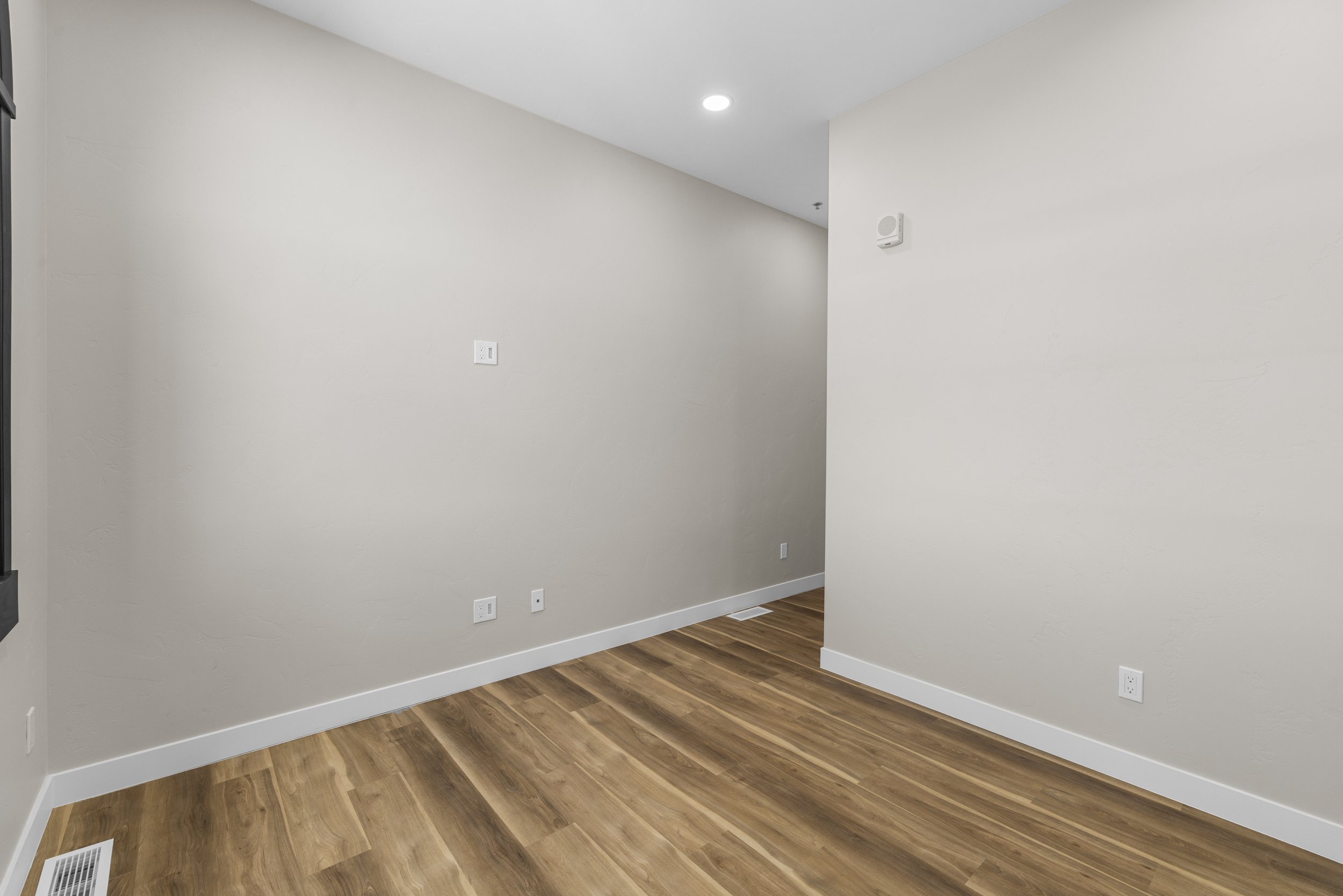 Empty room with white walls, hardwood floors, and ceiling lights.