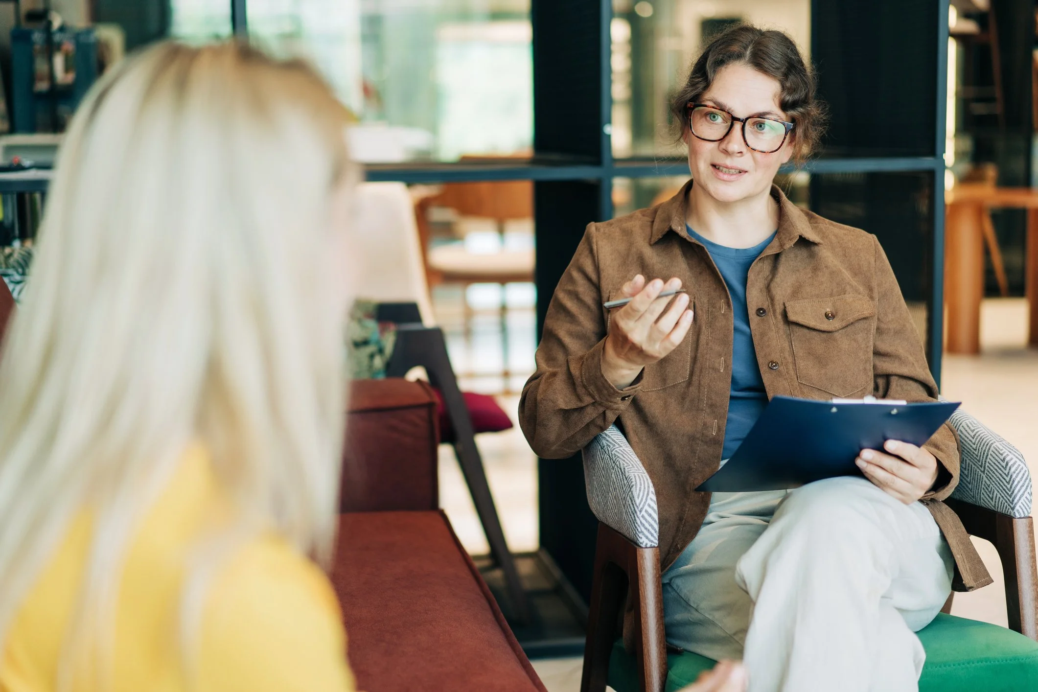 A therapist or counselor talking to a patient in a modern, cozy office.