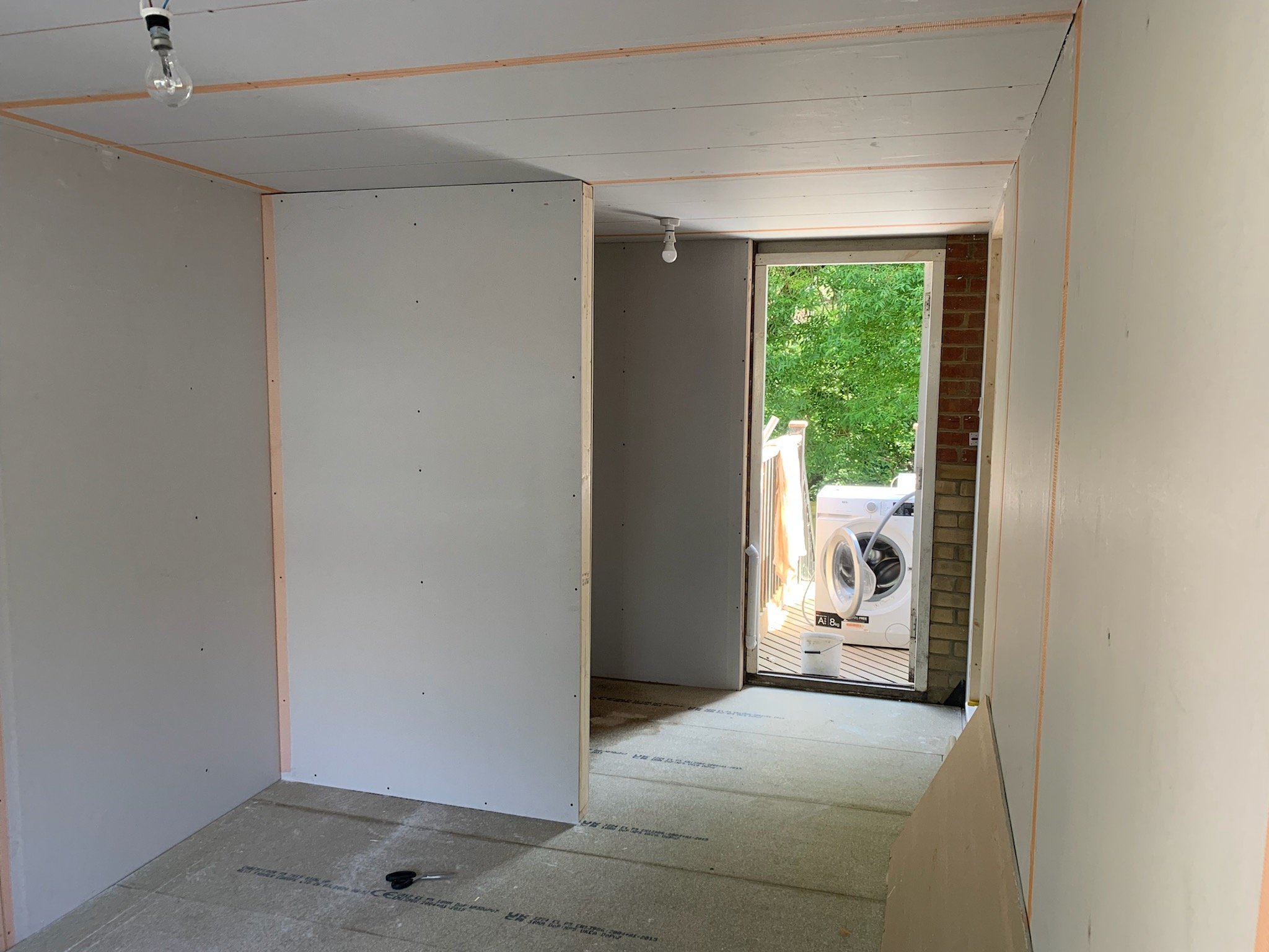 garage converted into room with plaster board on walls and empty door frame