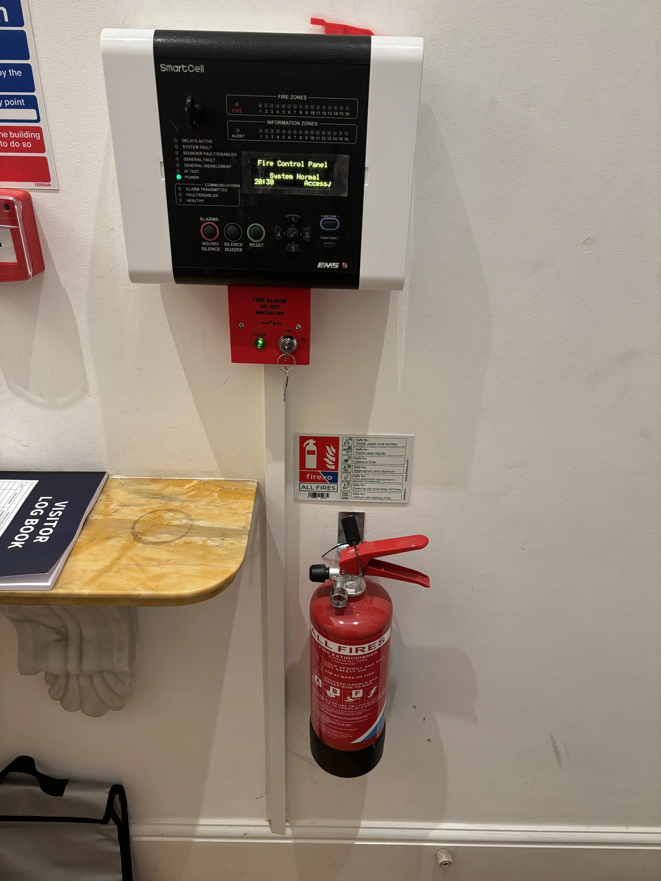 Electric fire alarm on wall with fire extinguisher