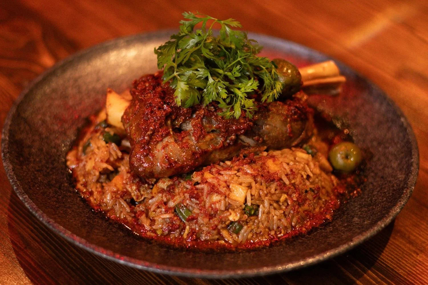 Braised lamb shank over fried rice topped with cilantro