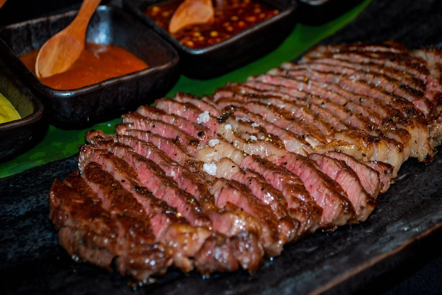 Sliced medium-rare wagyu steak with dipping sauces