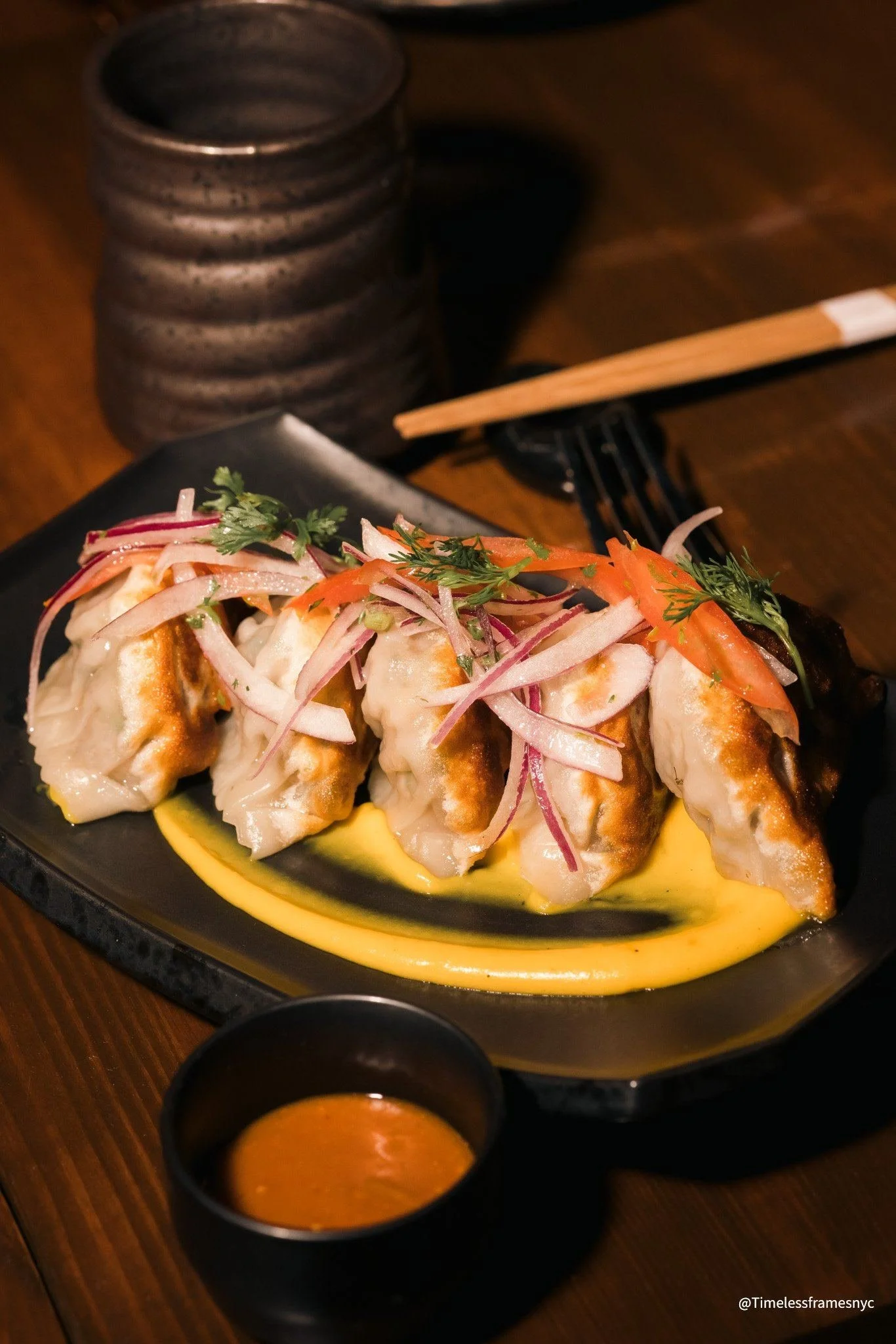 Potstickers with pickled onion and carrot over a yellow purée, with dipping sauce