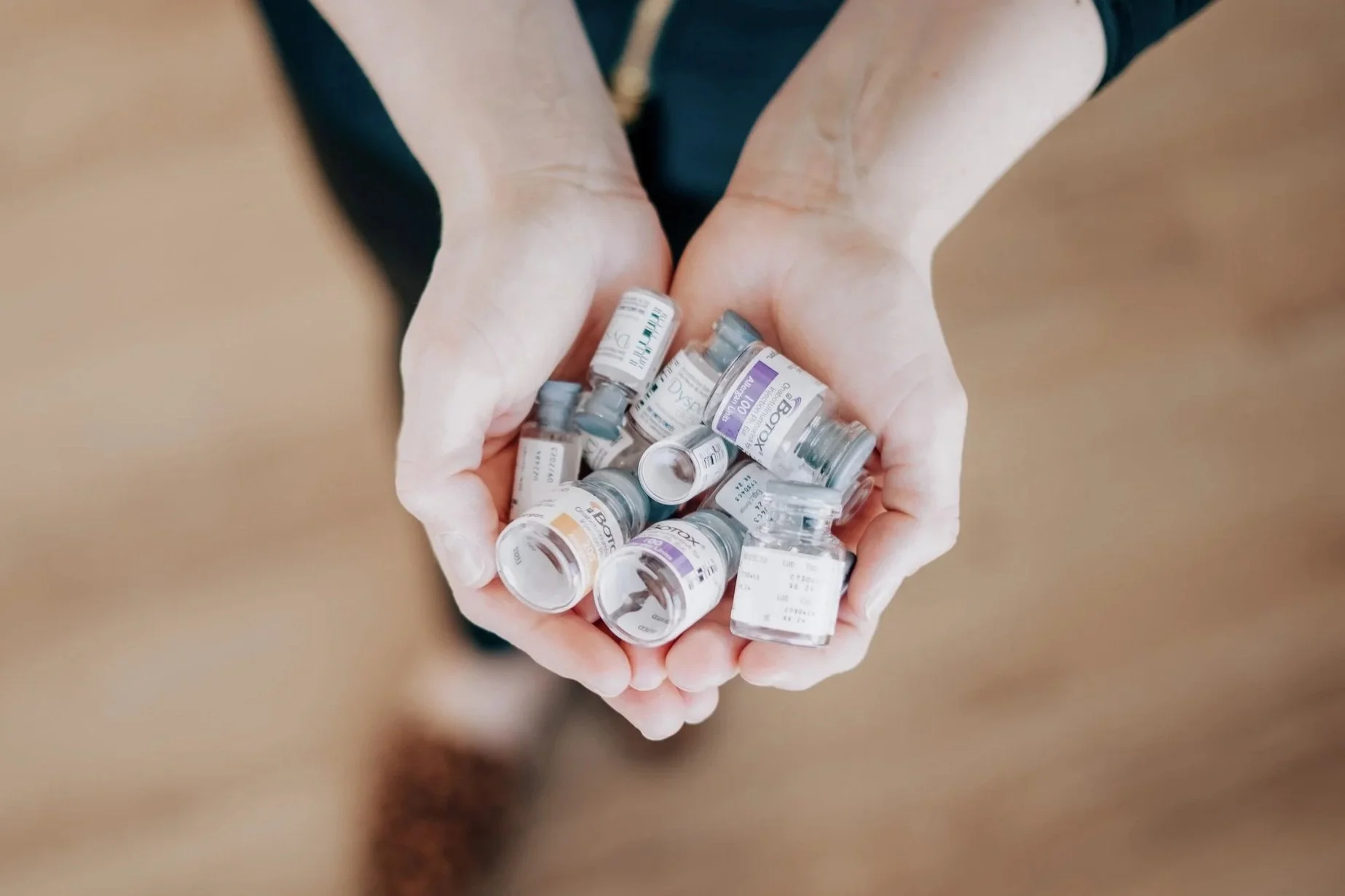 Hands holding multiple vaccine vials.