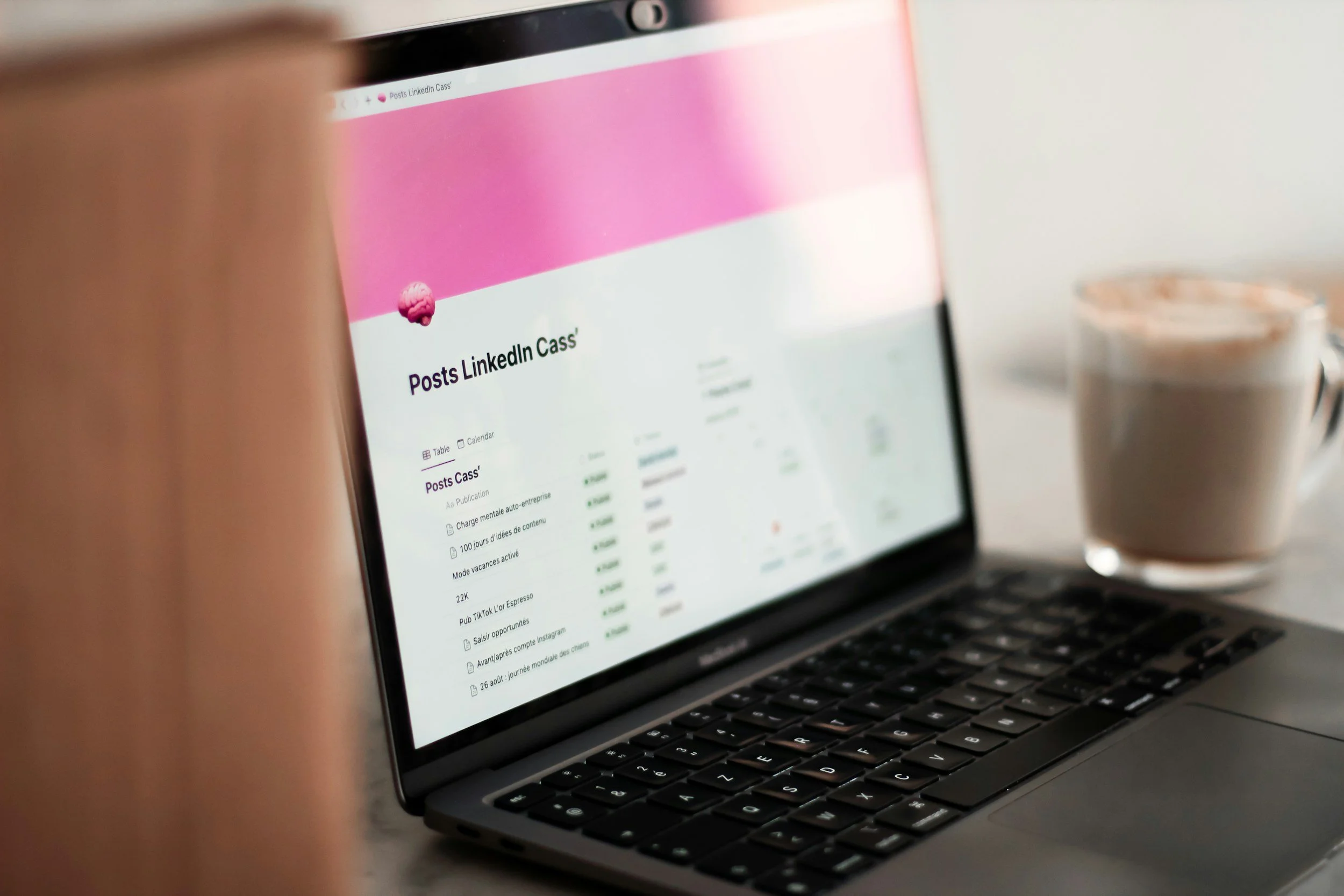 Close-up of a laptop screen displaying a LinkedIn profile page with the name 'Posts LinkedIn Cass' and a pink header, with a cup of coffee next to the laptop.