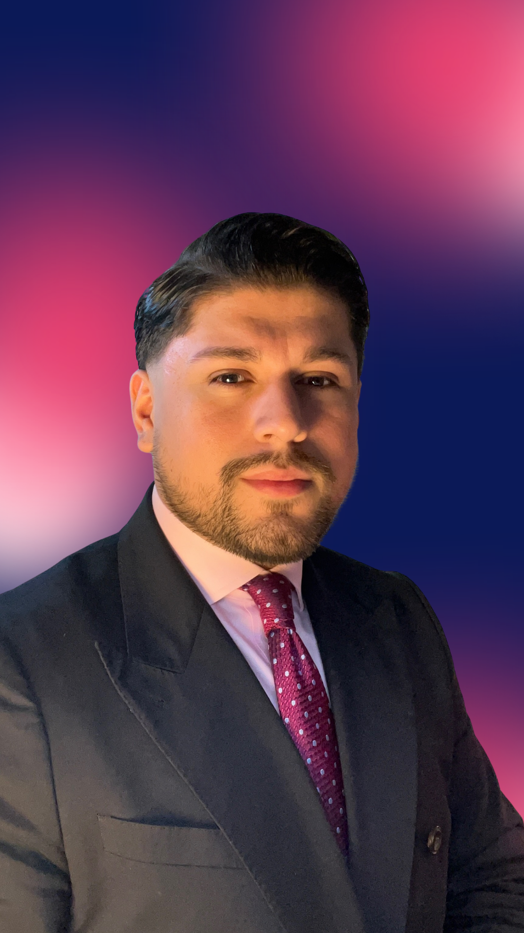 Diego Sanchez Rivas in a navy suit, pink shirt, and fuchsia patterned tie, posing against a blurred pink and blue gradient background.