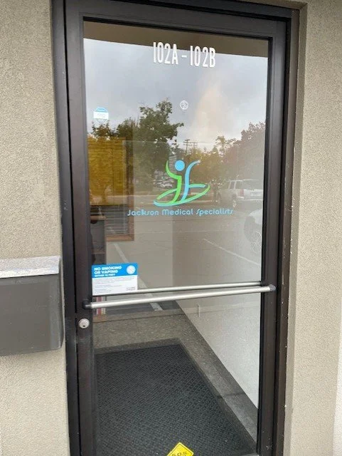 Glass door for Jackson Medical Specialists showing the logo on the door at Suite 102A, located at 650 E Pine St in Central Point, Oregon.