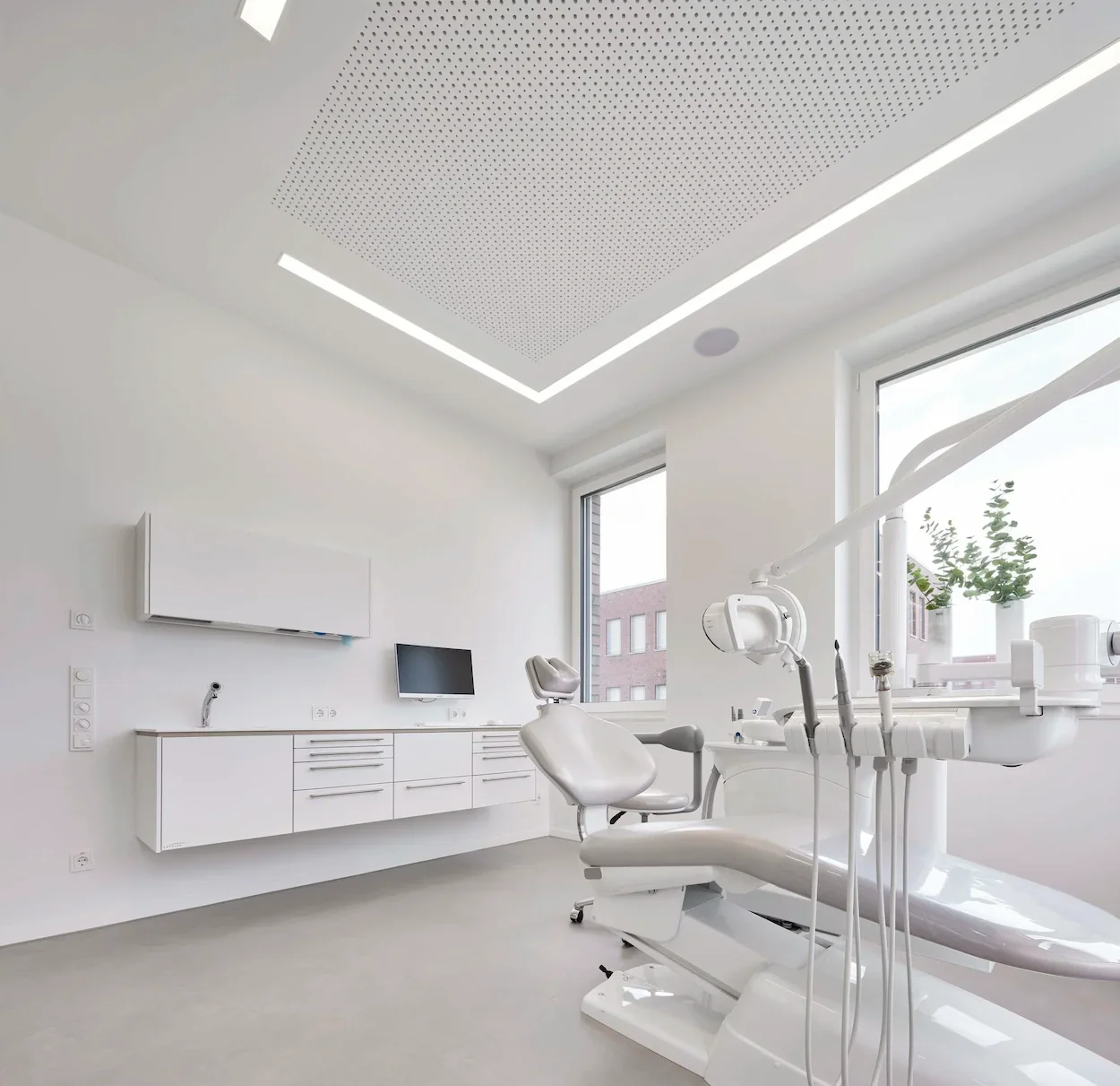 Helles Behandlungszimmer einer Kieferorthopädie mit moderner Behandlungseinheit und maßgefertigter Praxiseinrichtung.