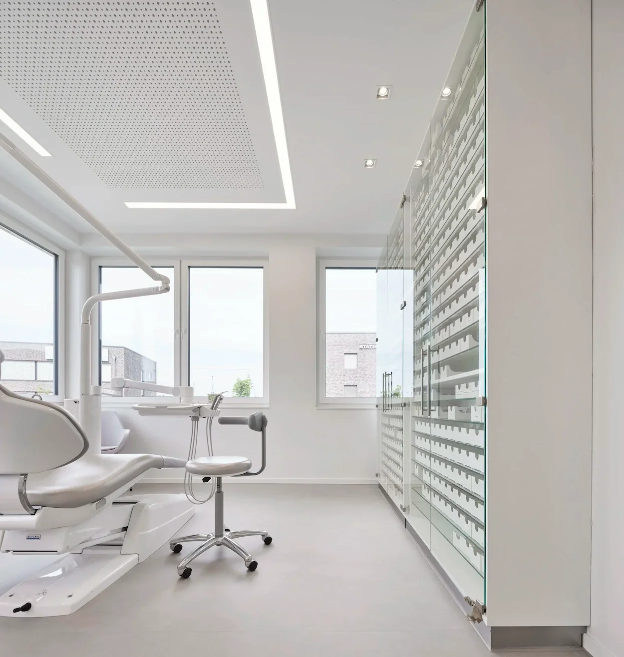 Helles Behandlungszimmer einer Kieferorthopädie mit moderner Praxiseinrichtung und Glas-Sichtschutz