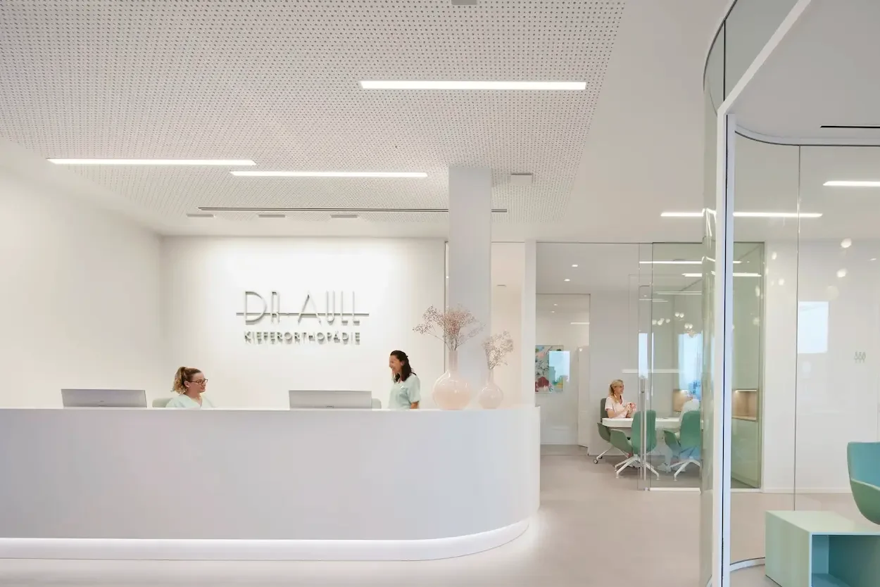 Moderner Wartebereich einer Kieferorthopädie mit mintgrüner Sitzlandschaft, Leseecke und hochwertigem Praxisdesign