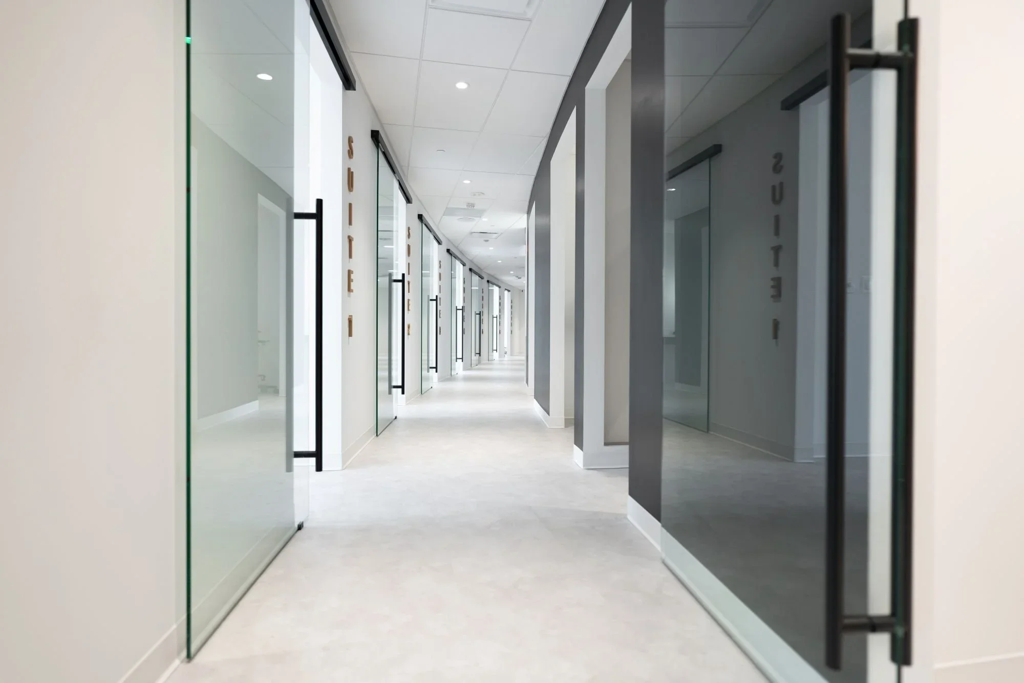 Moderner Praxisflur mit verglasten Behandlungsräumen und durchdachter Innenarchitektur für Facharztpraxen.