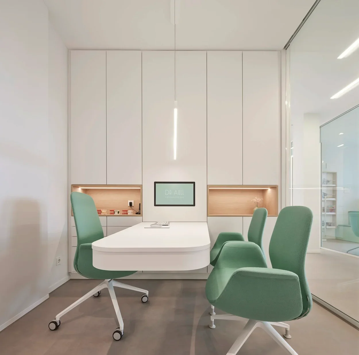 Modernes Beratungszimmer einer Kieferorthopädie mit mintgrünen Stühlen und maßgefertigter Praxiseinrichtung