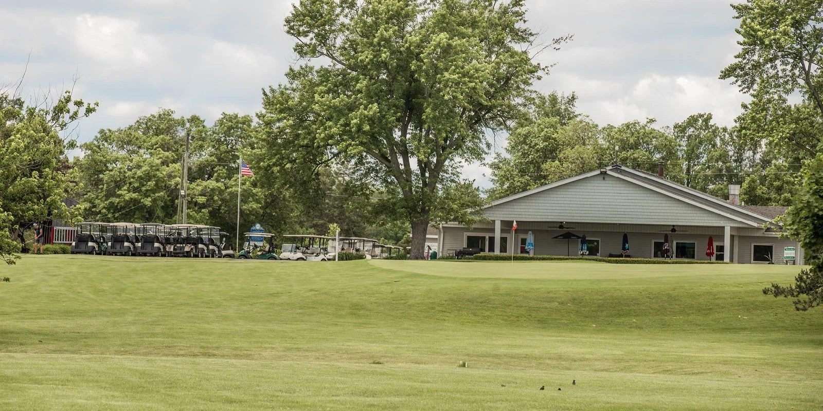 Golf course clubhouse with parked golf carts and trees.