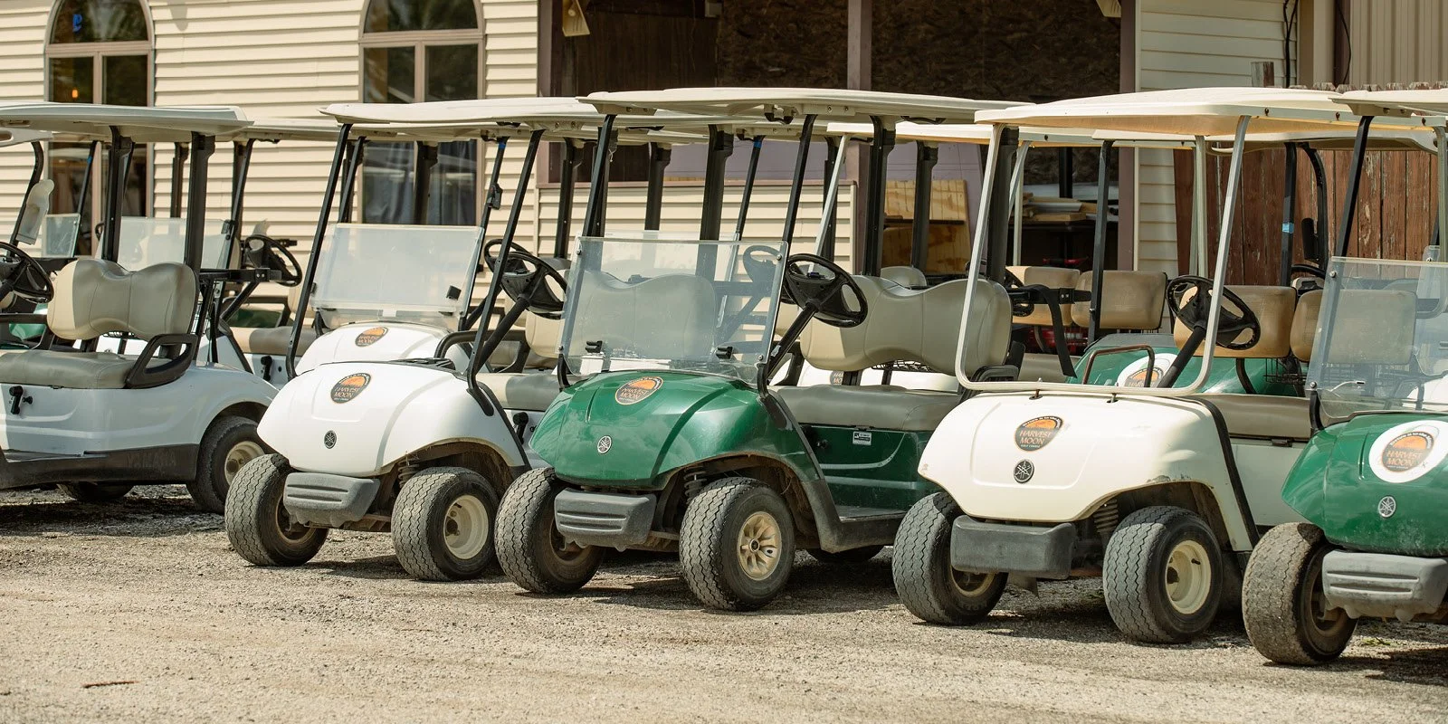 Several golf carts parked outdoors in front of a building.