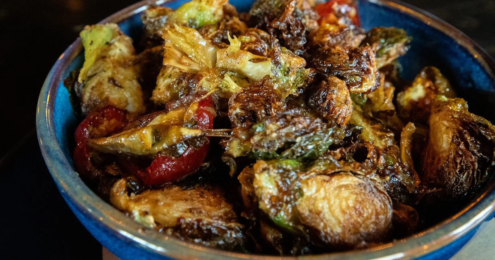 A bowl filled with roasted vegetables including eggplant, red bell peppers, and green peppers.