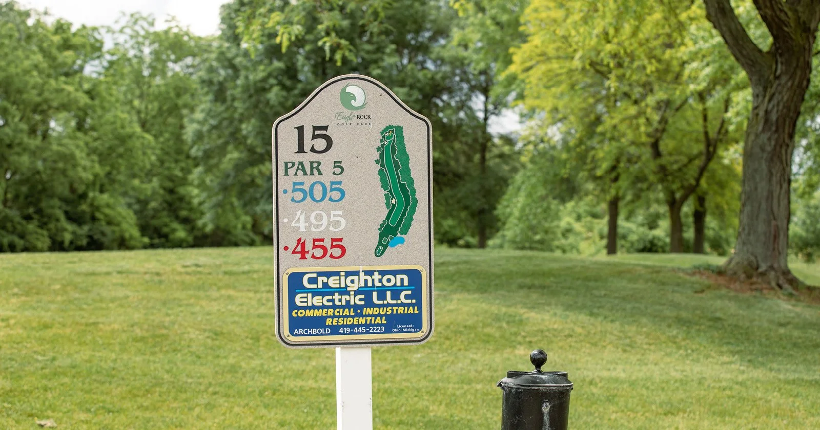 Golf course sign indicating hole 15, a par 5, with yardages of 505, 495, and 455 yards from different tees. The sign advertises Creighton Electric LLC, with contact information and licensing details, located in Archbold, Ohio.