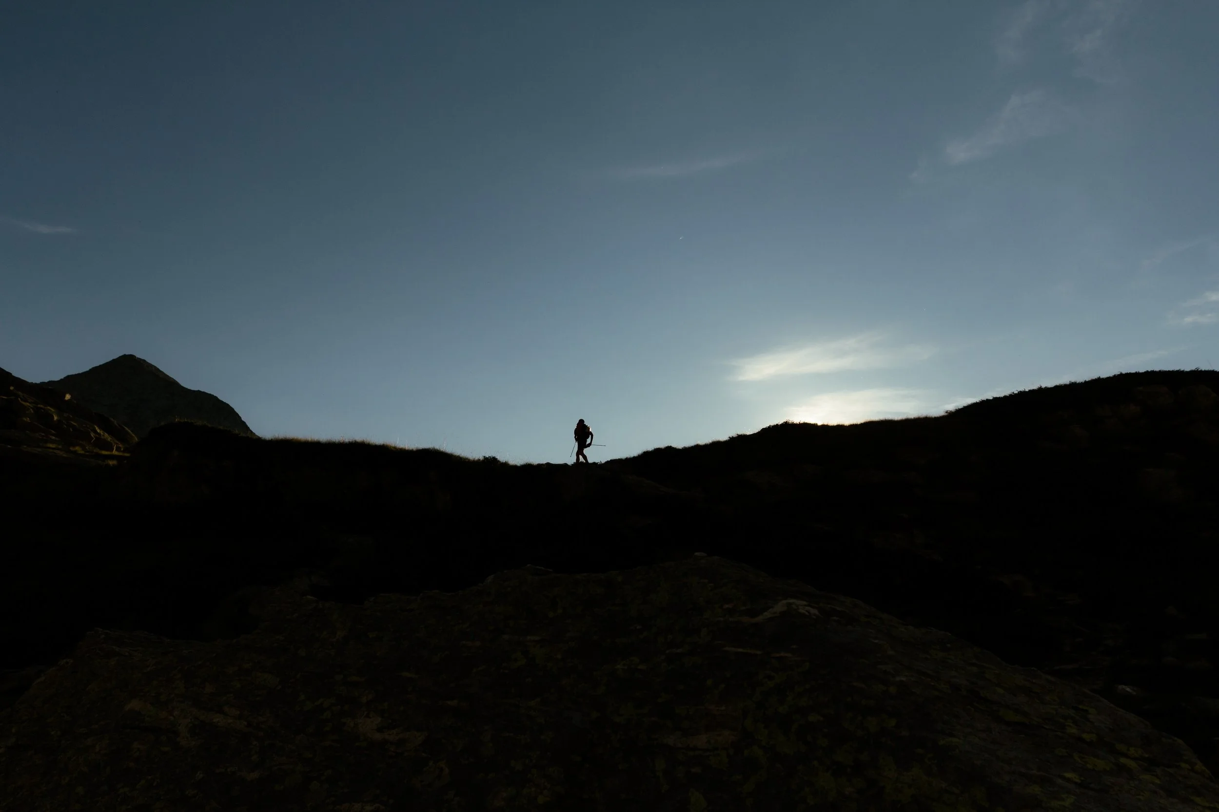 Escursionista in salita su un sentiero montano al tramonto o all'alba