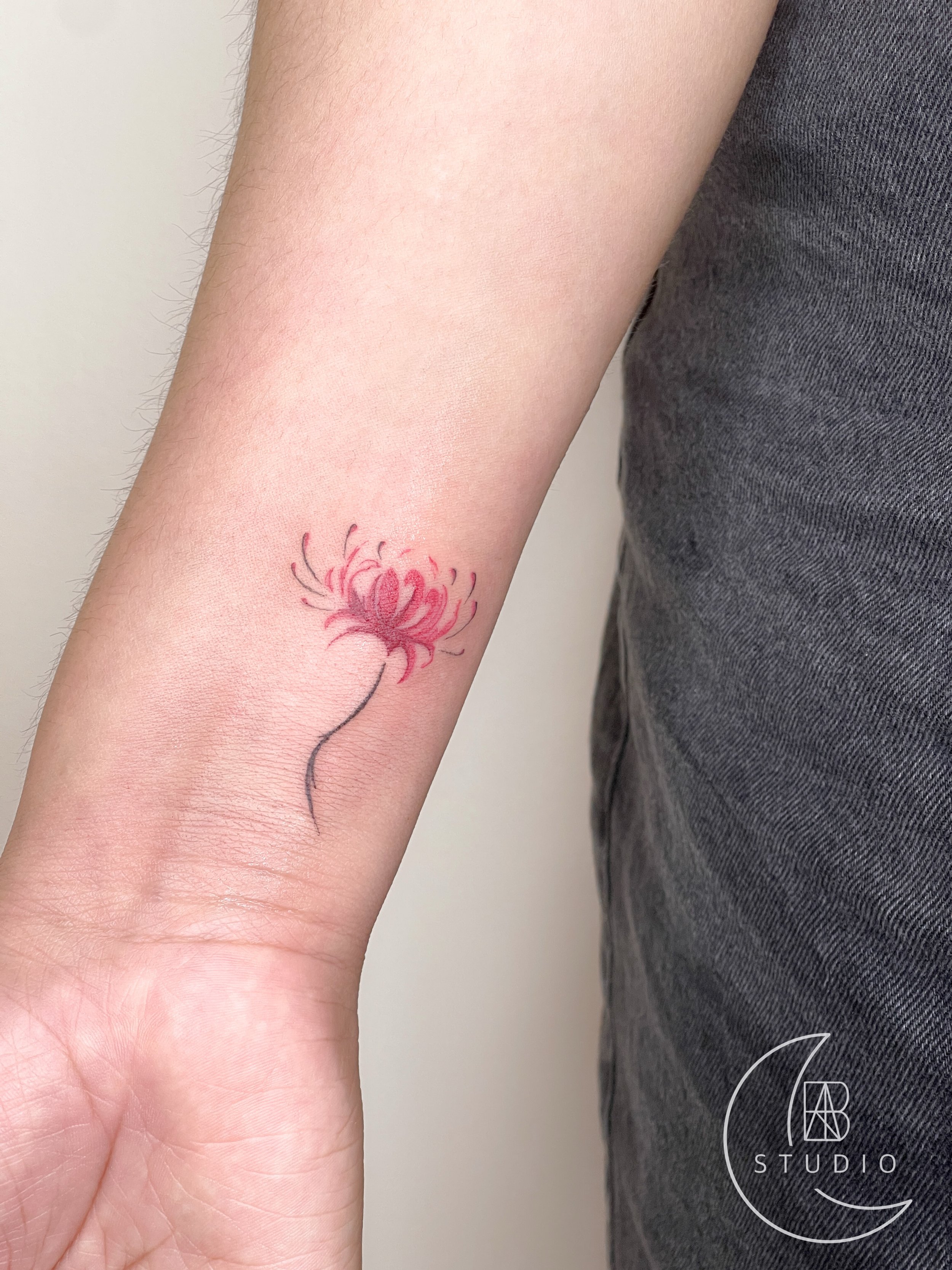 fine linework of spider lily tattoo on the wrist area