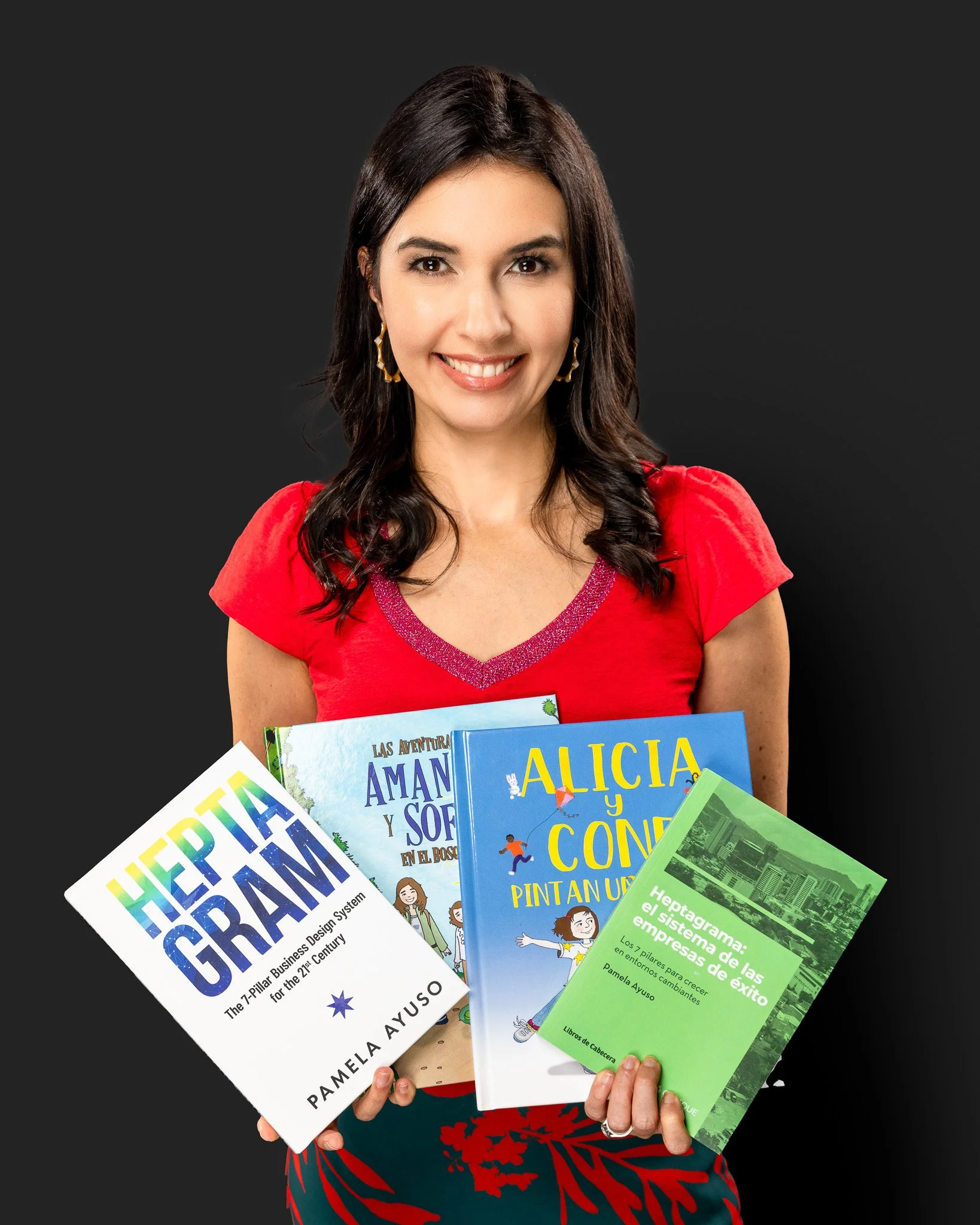 Una mujer sonriente con cabello oscuro y ropa roja sostiene varios libros, incluyendo uno sobre diseño empresarial, uno infantil y uno sobre el éxito empresarial.