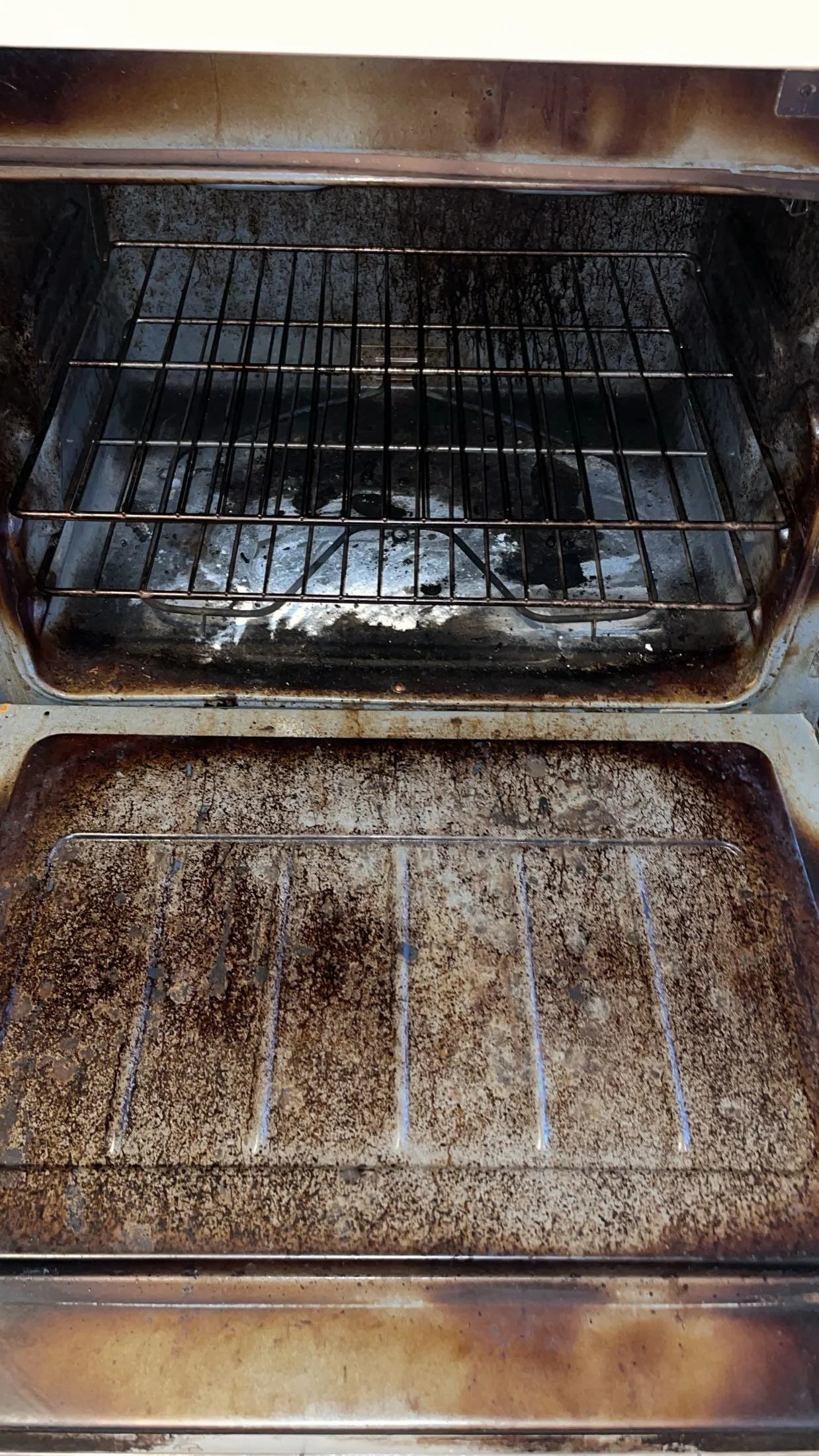 The interior of a dirty oven with grime and burnt residue on the oven floor, walls, and racks.