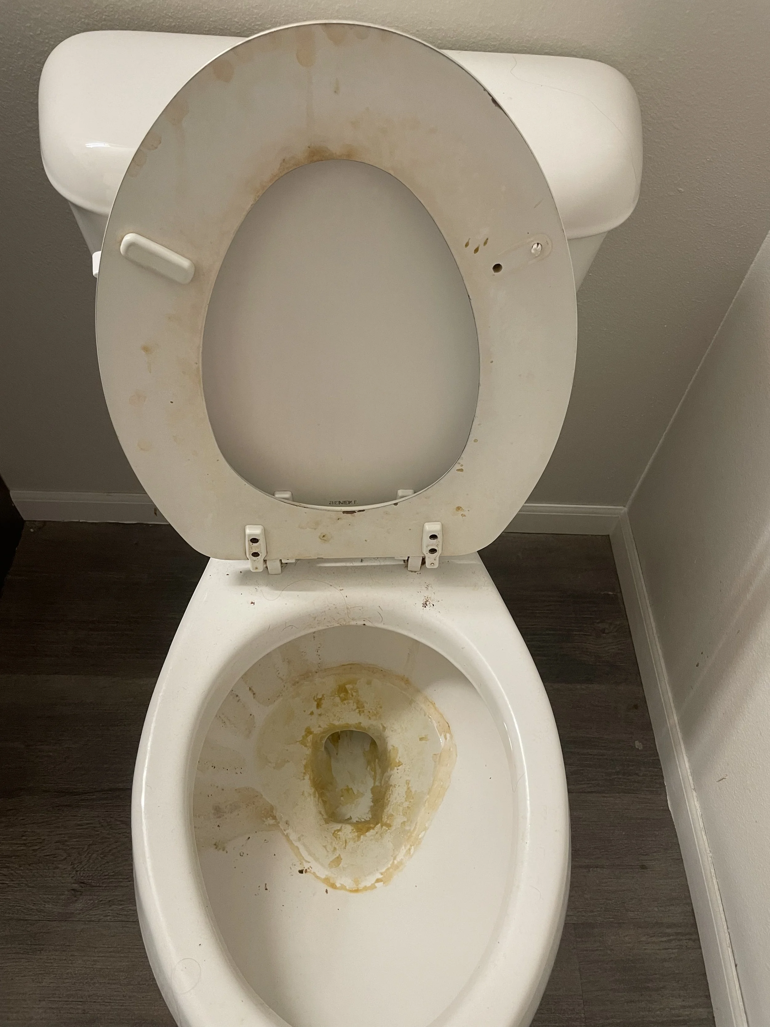 Dirty and stained toilet with an open lid, showing yellowish stains and grime inside the bowl and on the seat rim.