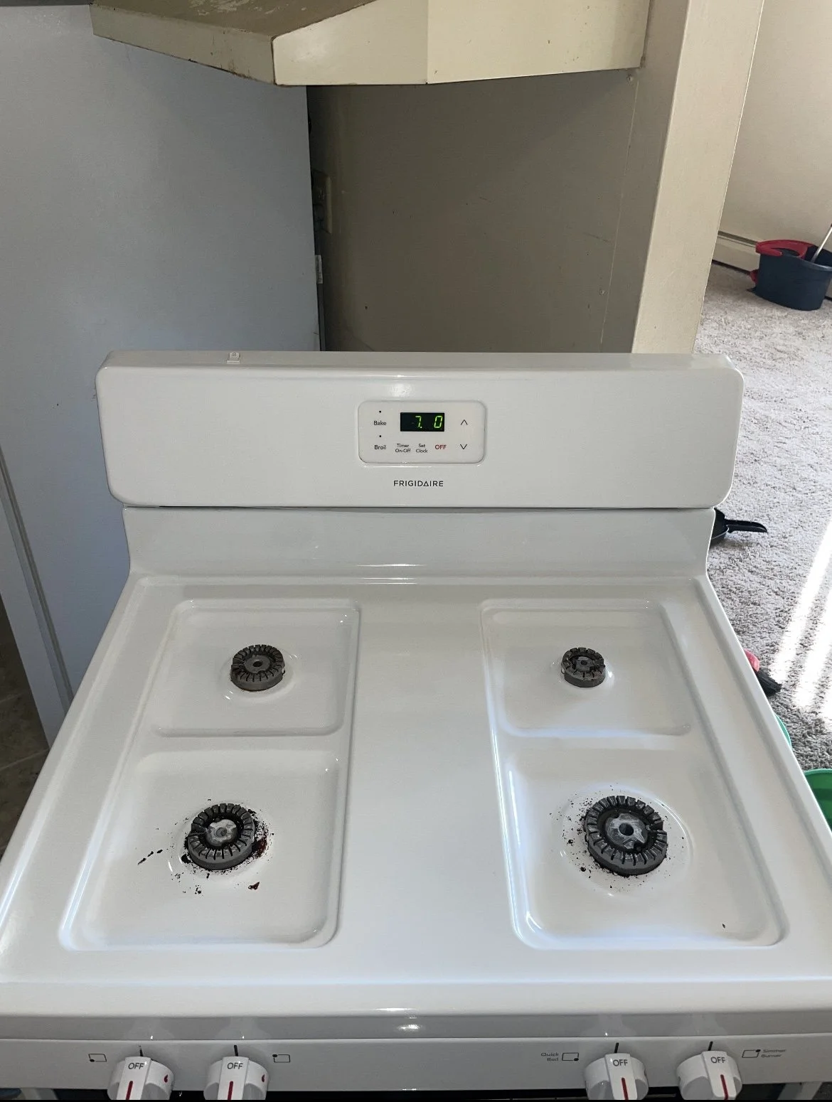 White Frigidaire electric stove with four burners, some burners stained, digital timer showing 7 minutes, and control knobs at the front.