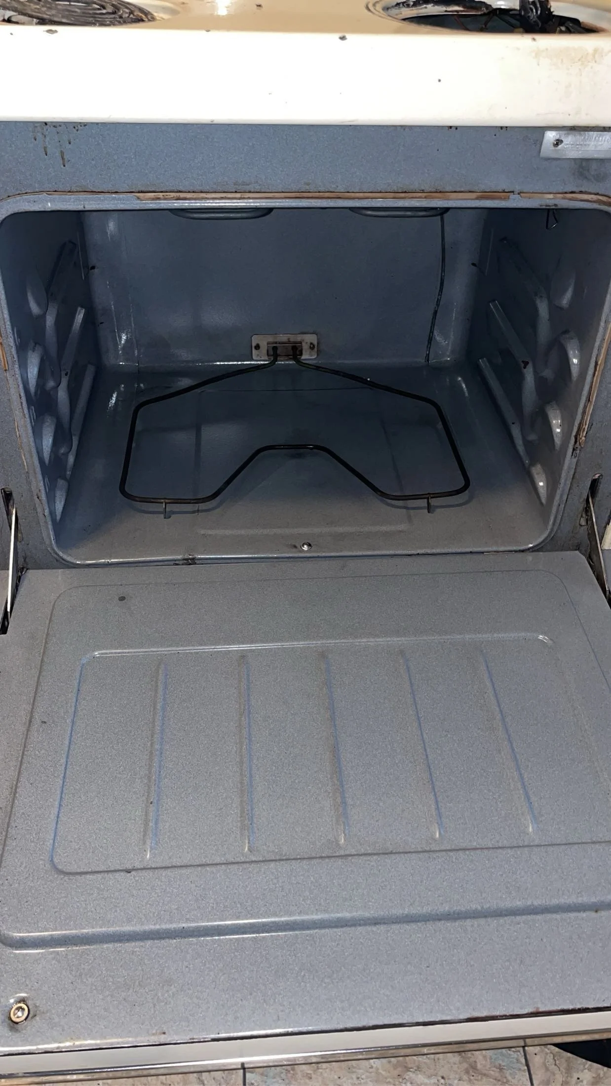 An empty microwave oven with a metal wire rack inside and a glass turntable at the bottom.
